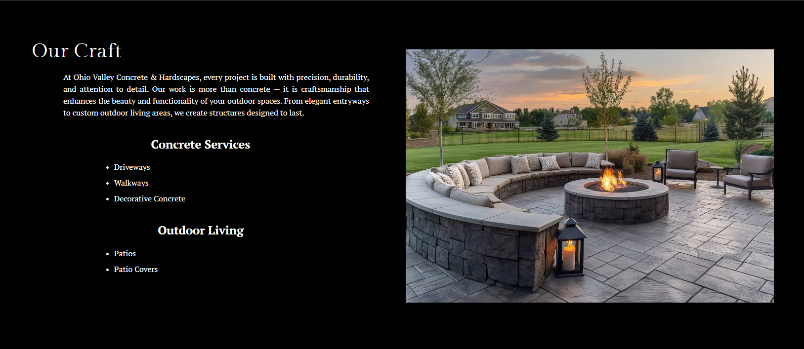 An outdoor patio with a circular stone fire pit, surrounded by cushioned chairs and lanterns, overlooking a grassy backyard at sunset.