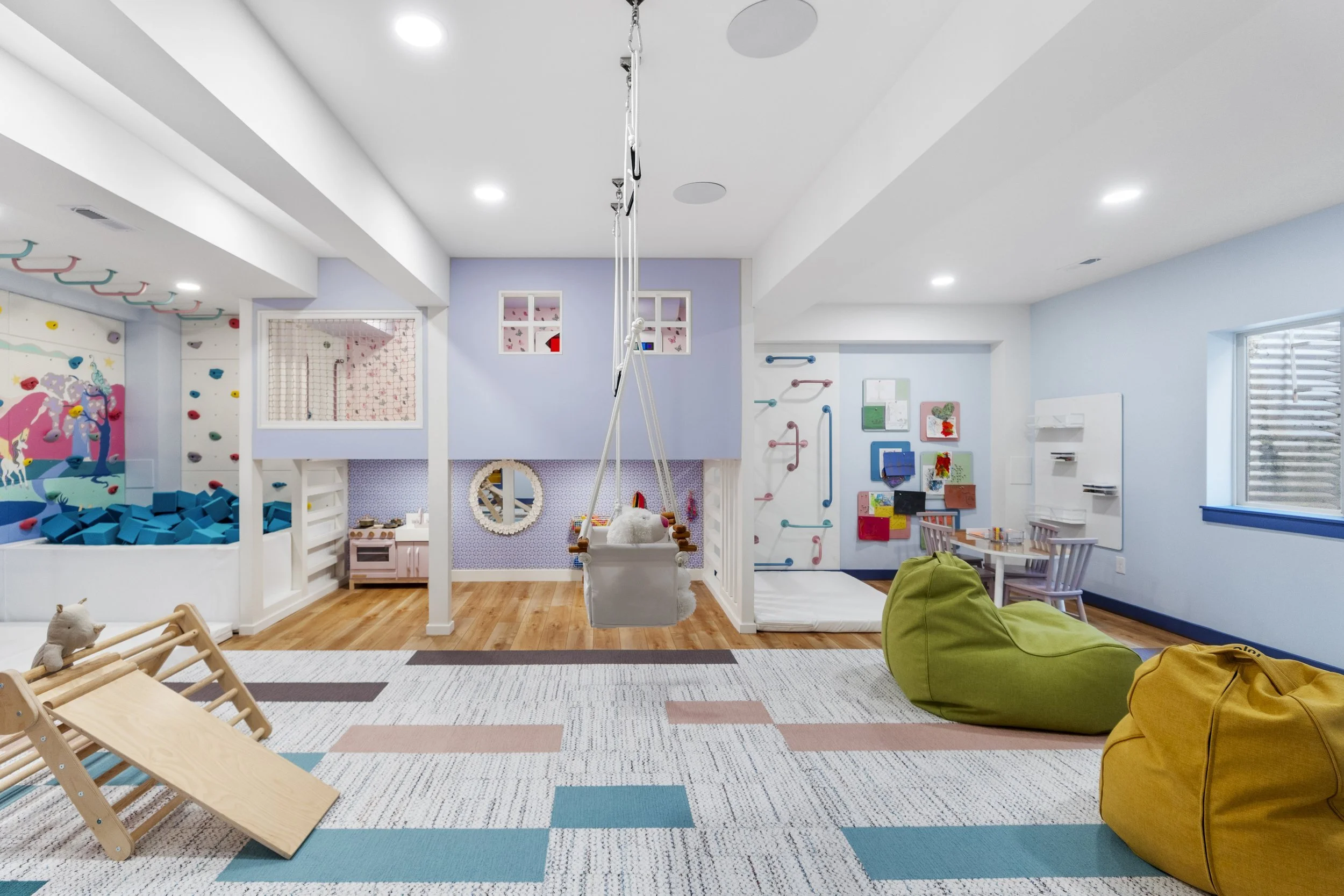 Finished basement playroom with a climbing wall and foam pit