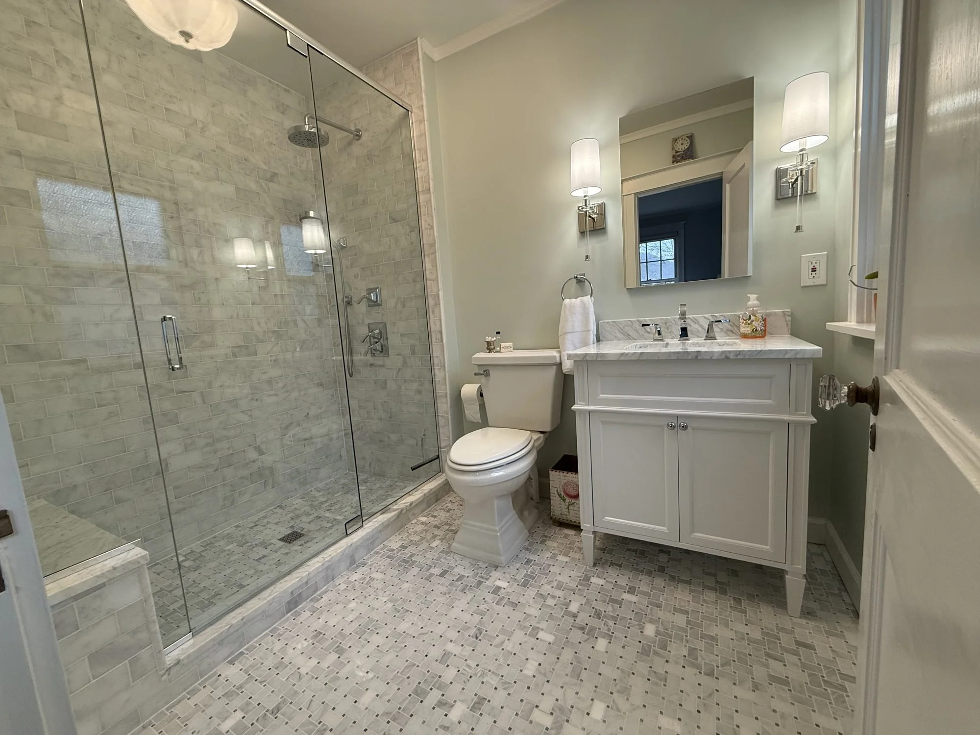 Glass-enclosed walk-in shower beside a white vanity