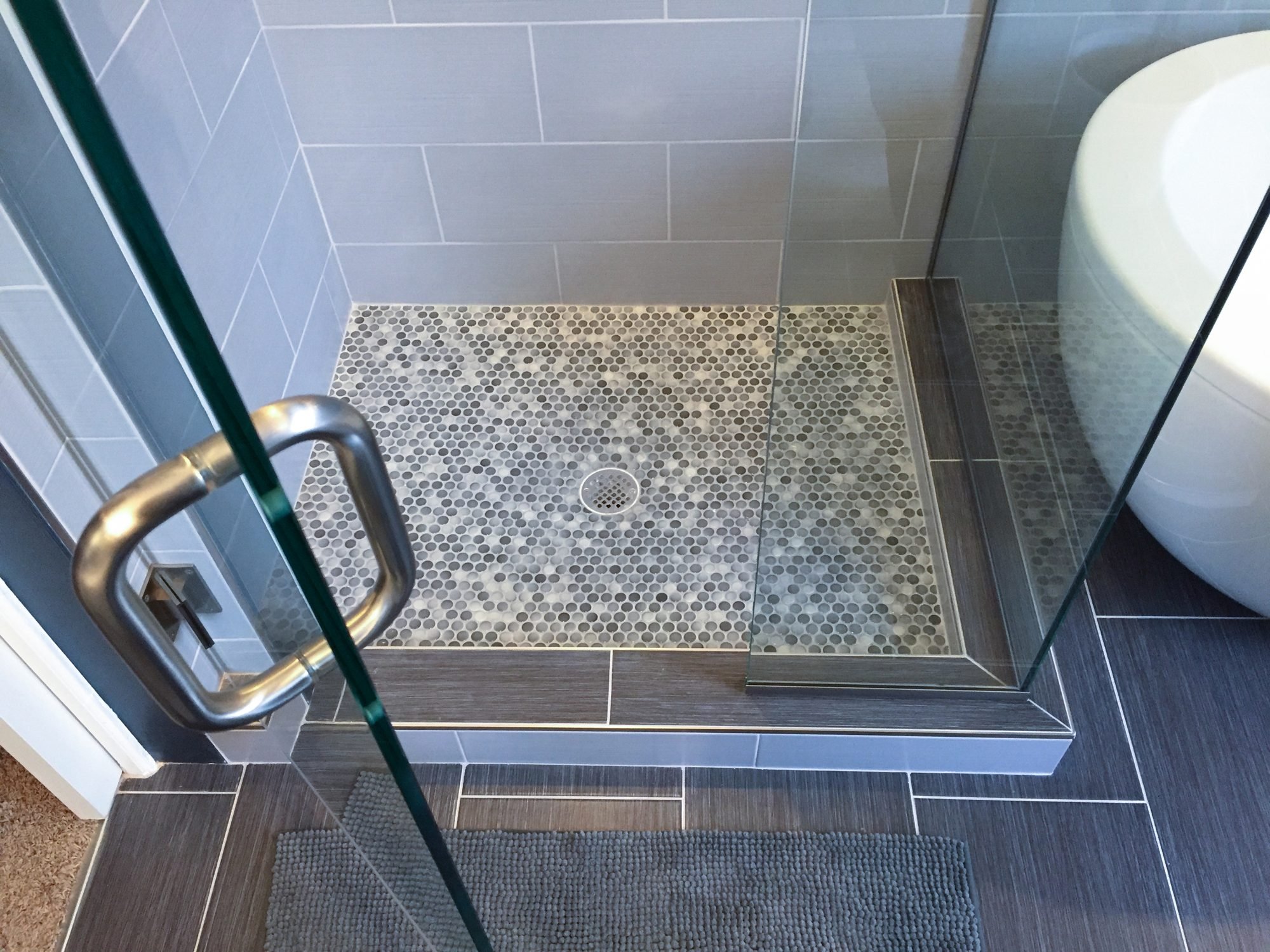 Walk-in shower with a pebble tile floor and glass door
