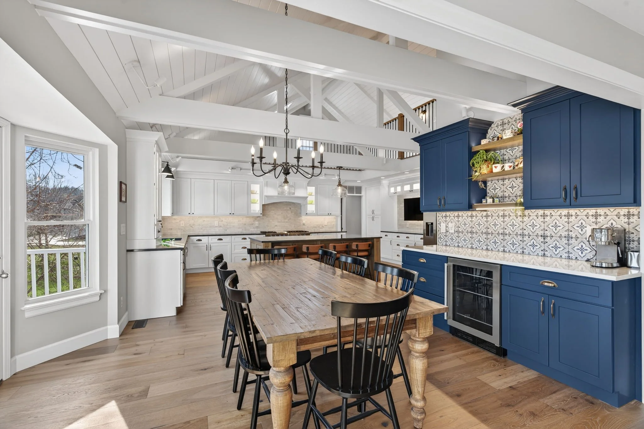 Dining table beside navy cabinetry and a patterned tile backsplash