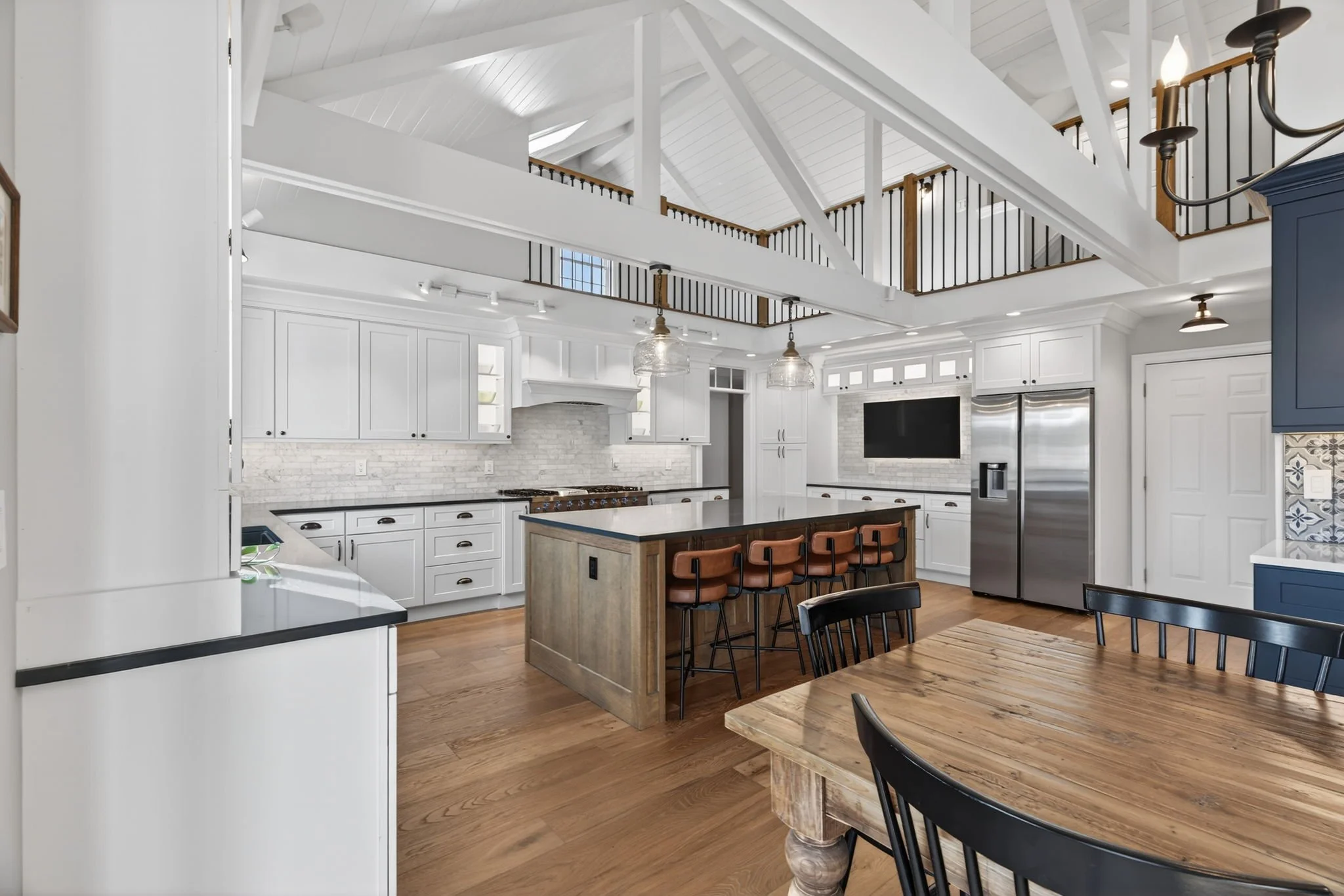 Open kitchen under a vaulted, beamed ceiling with a stained wood island