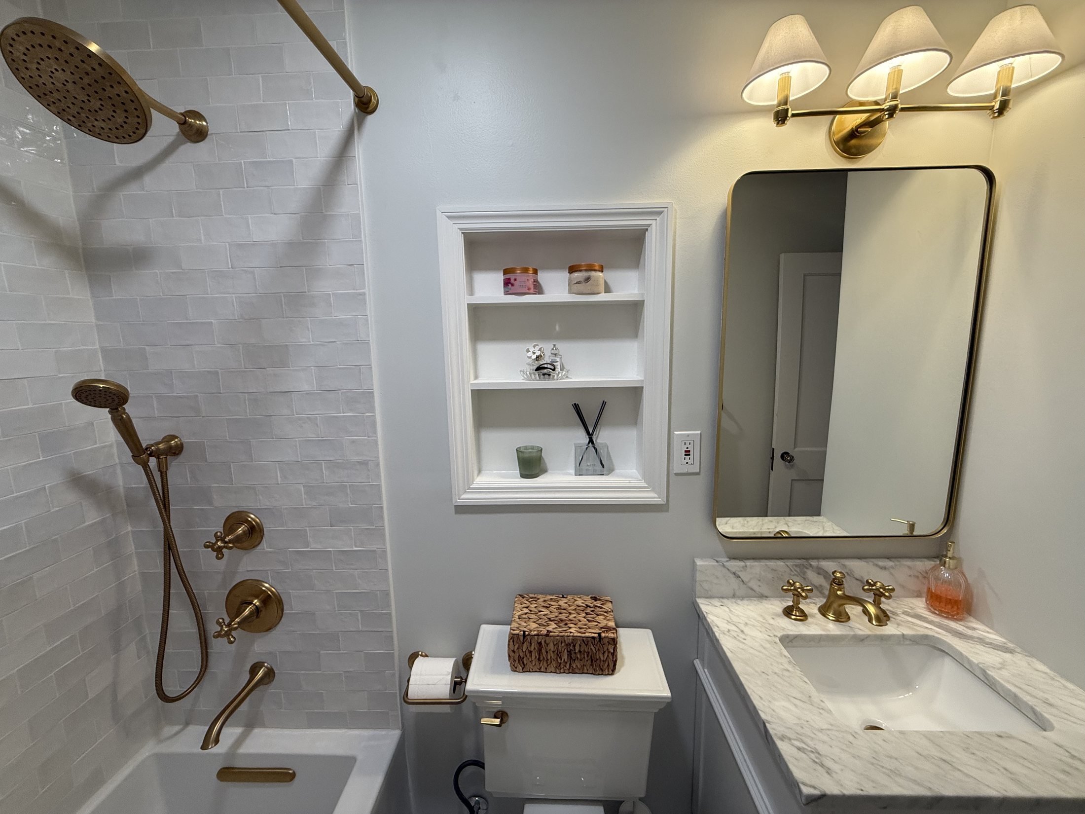 Brass shower fixtures and a recessed wall shelf