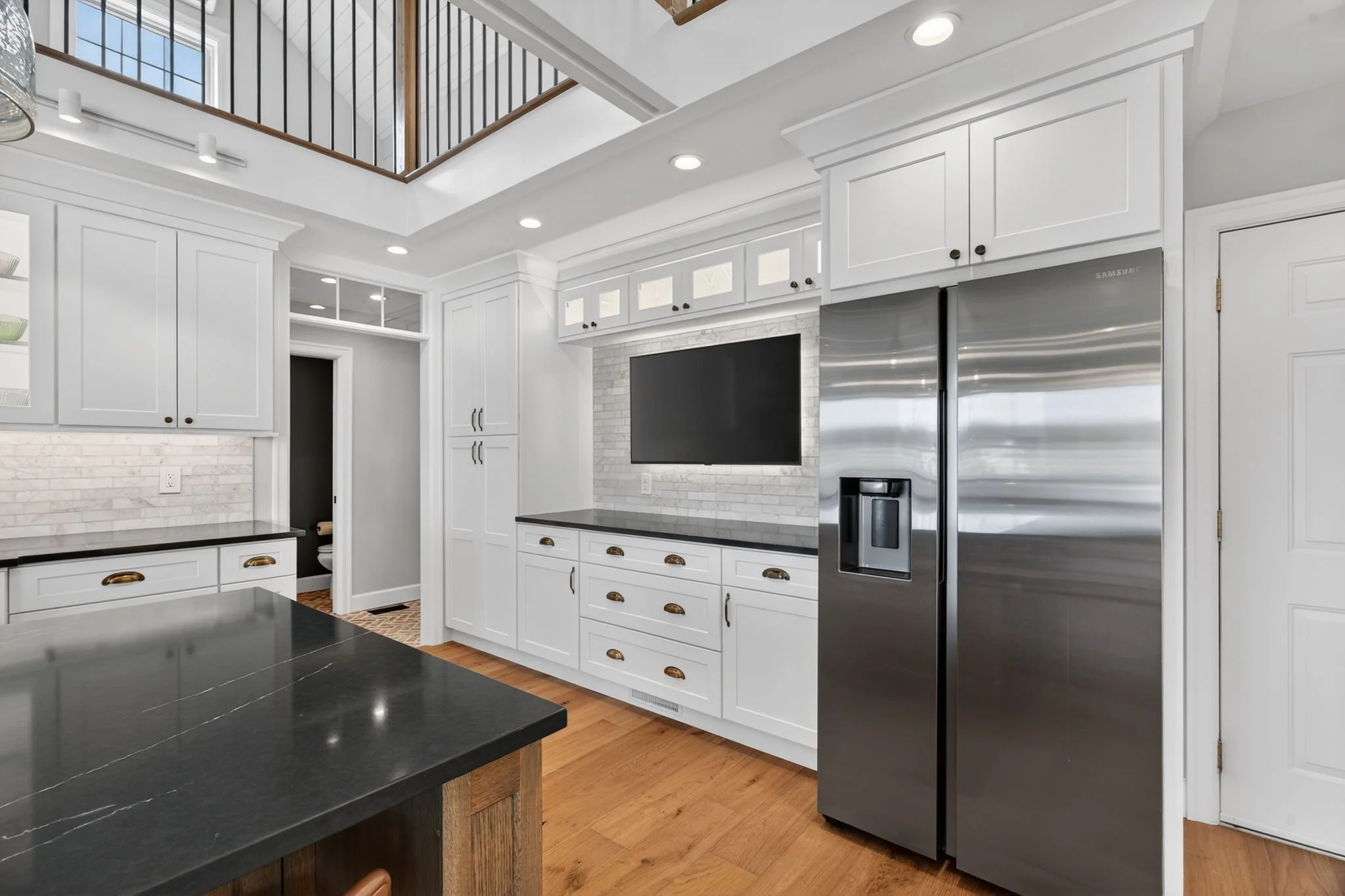 White cabinetry with a built-in refrigerator and TV niche
