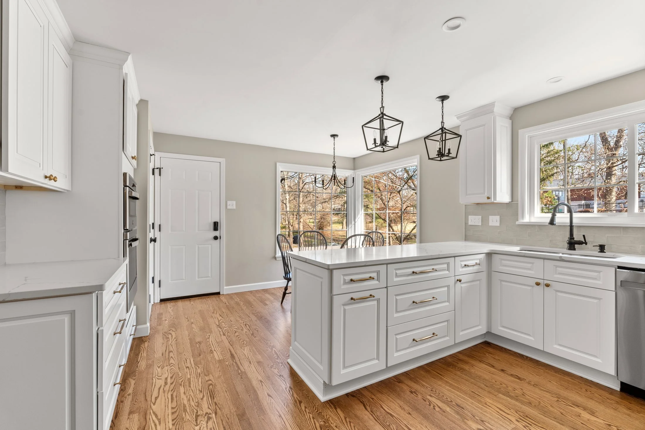 White kitchen peninsula with lantern pendants