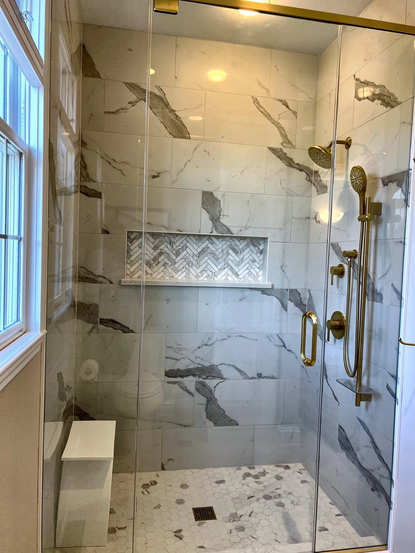 Marble-look shower with a herringbone niche and bench