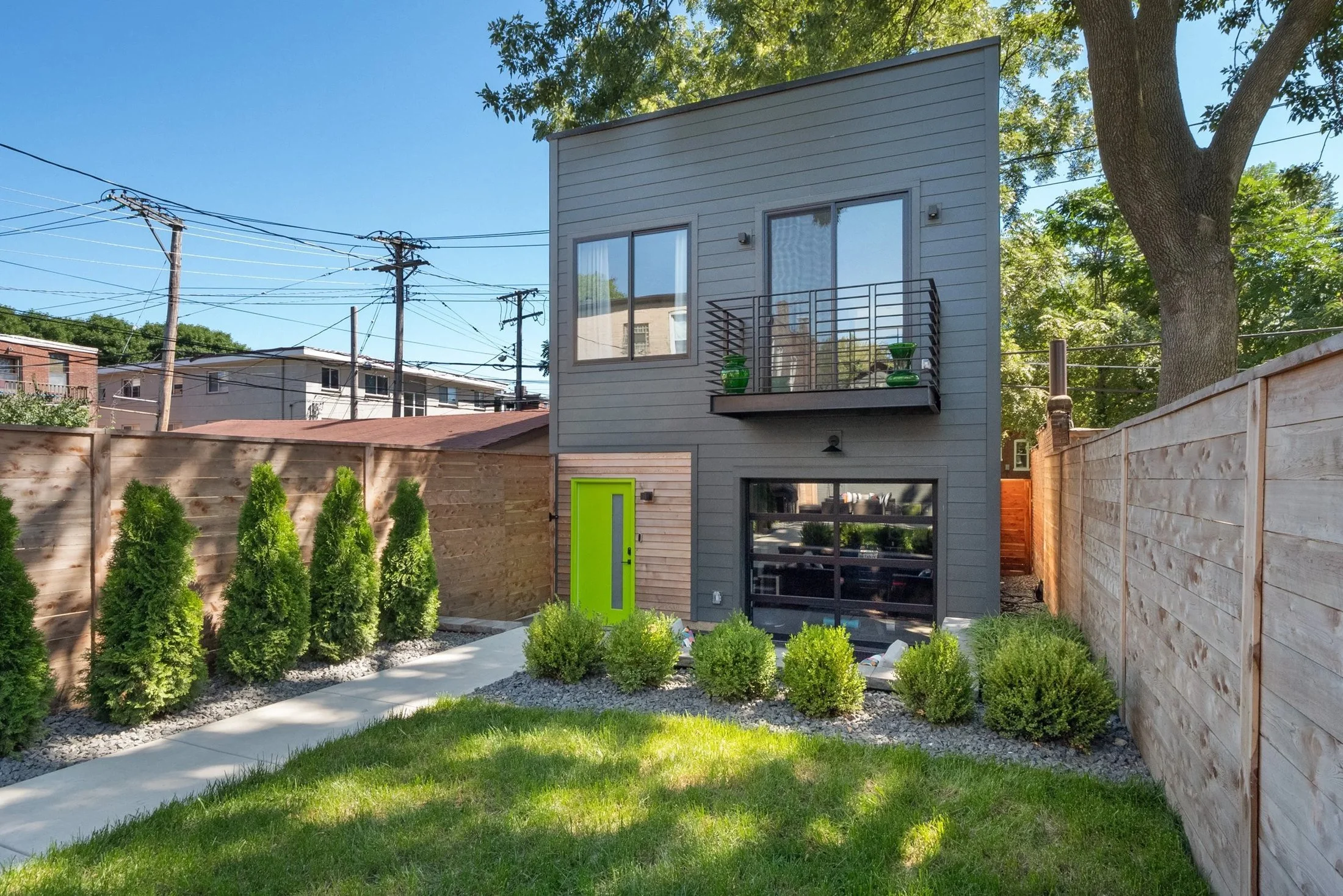 Landscaped backyard with a lawn, arborvitae, and wood fence