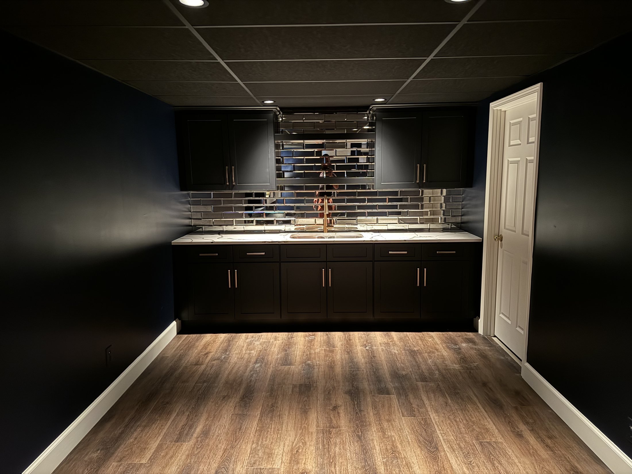 Black wet bar with a tile backsplash