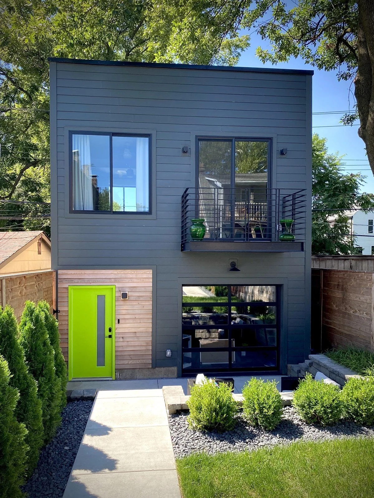 Modern carriage house with dark lap siding, a balcony, and a glass garage door