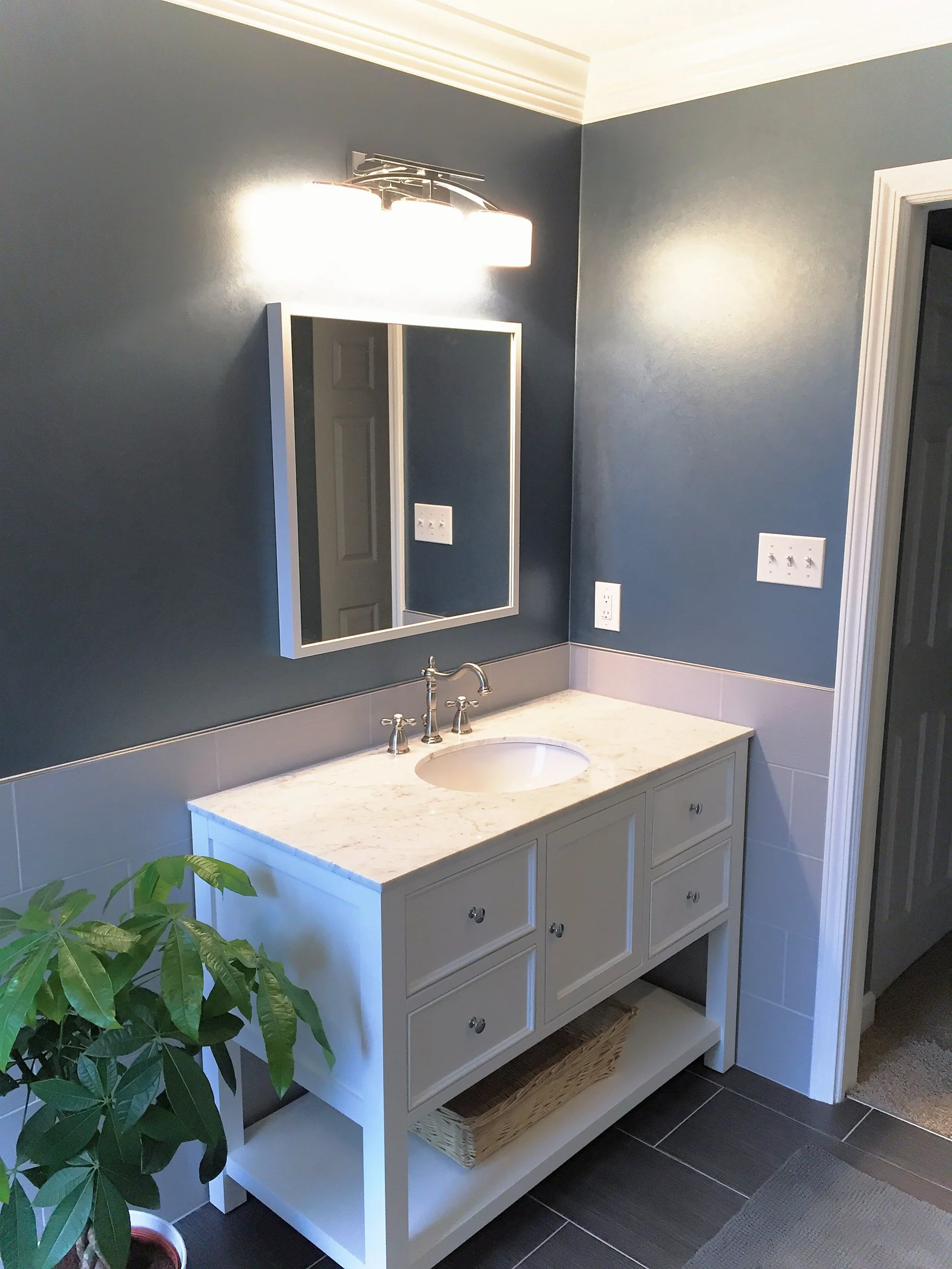 White vanity with a marble top and navy walls