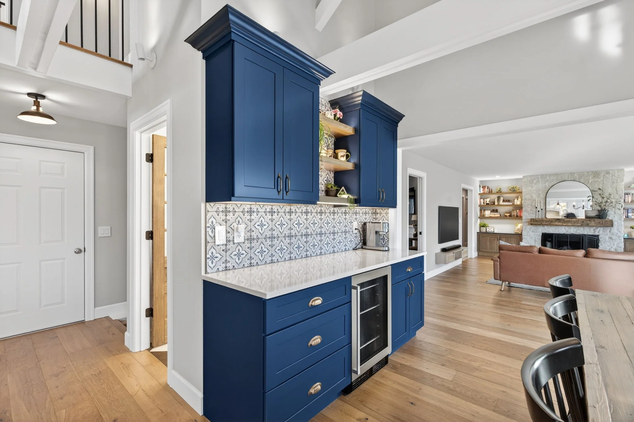 Navy blue kitchen cabinetry with a wine fridge and patterned tile backsplash