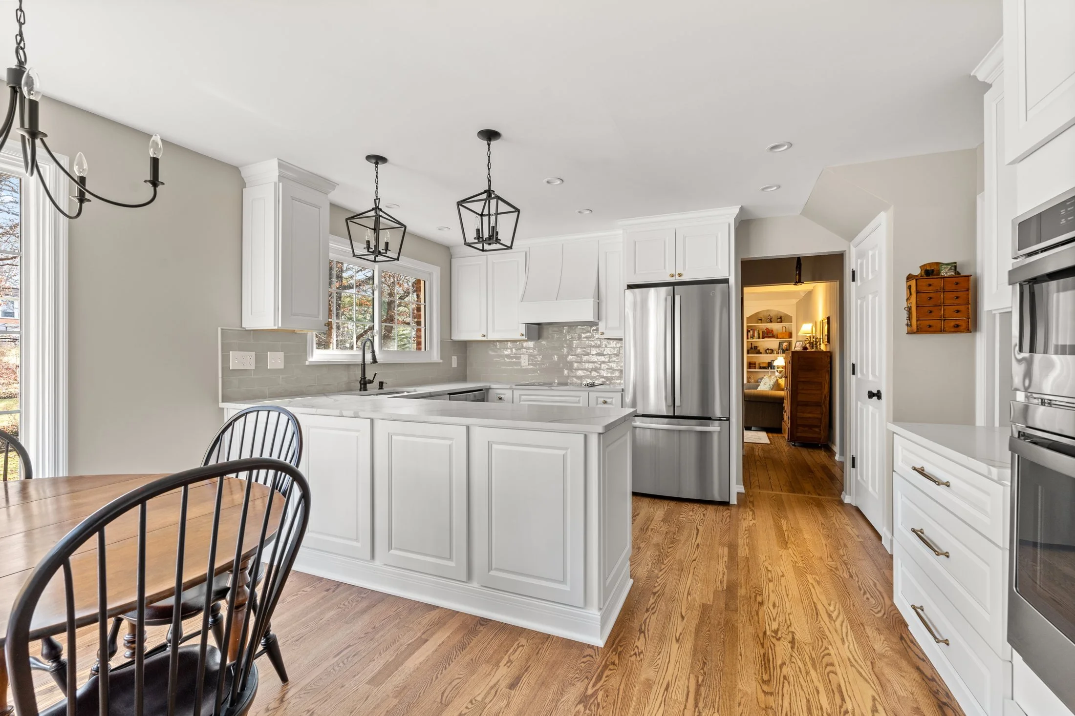 White kitchen with a breakfast table and lantern pendants