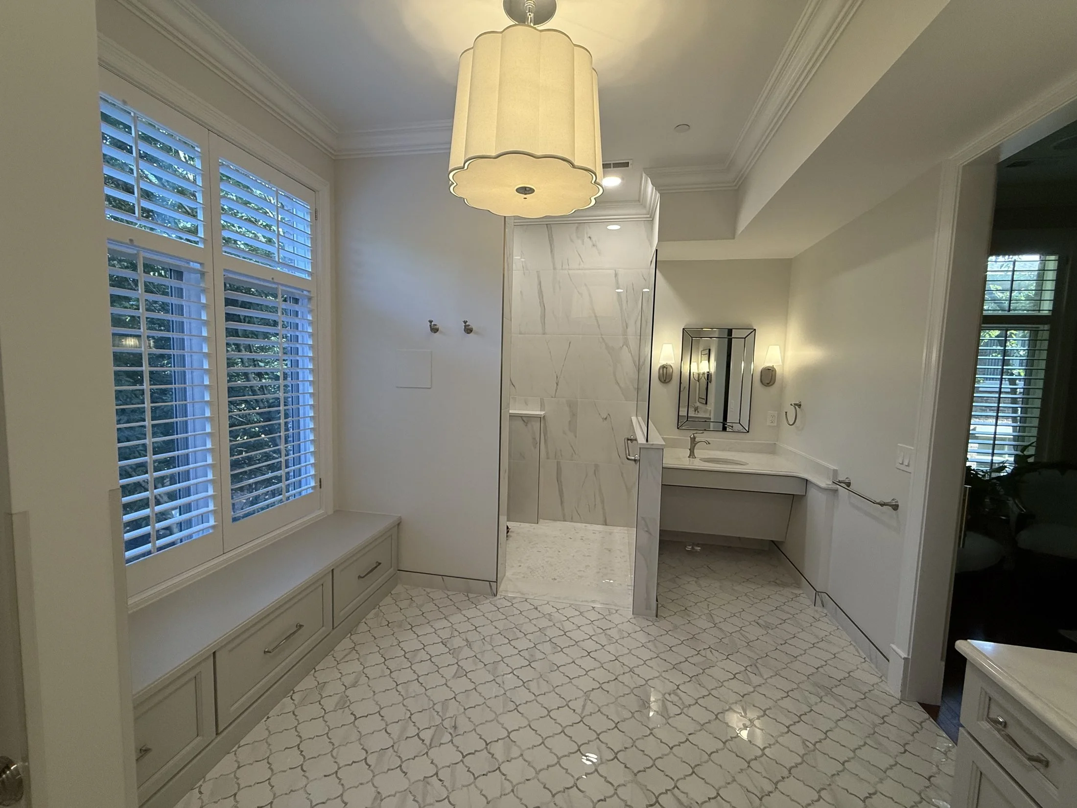 Window seat and walk-in shower in a marble-look bath