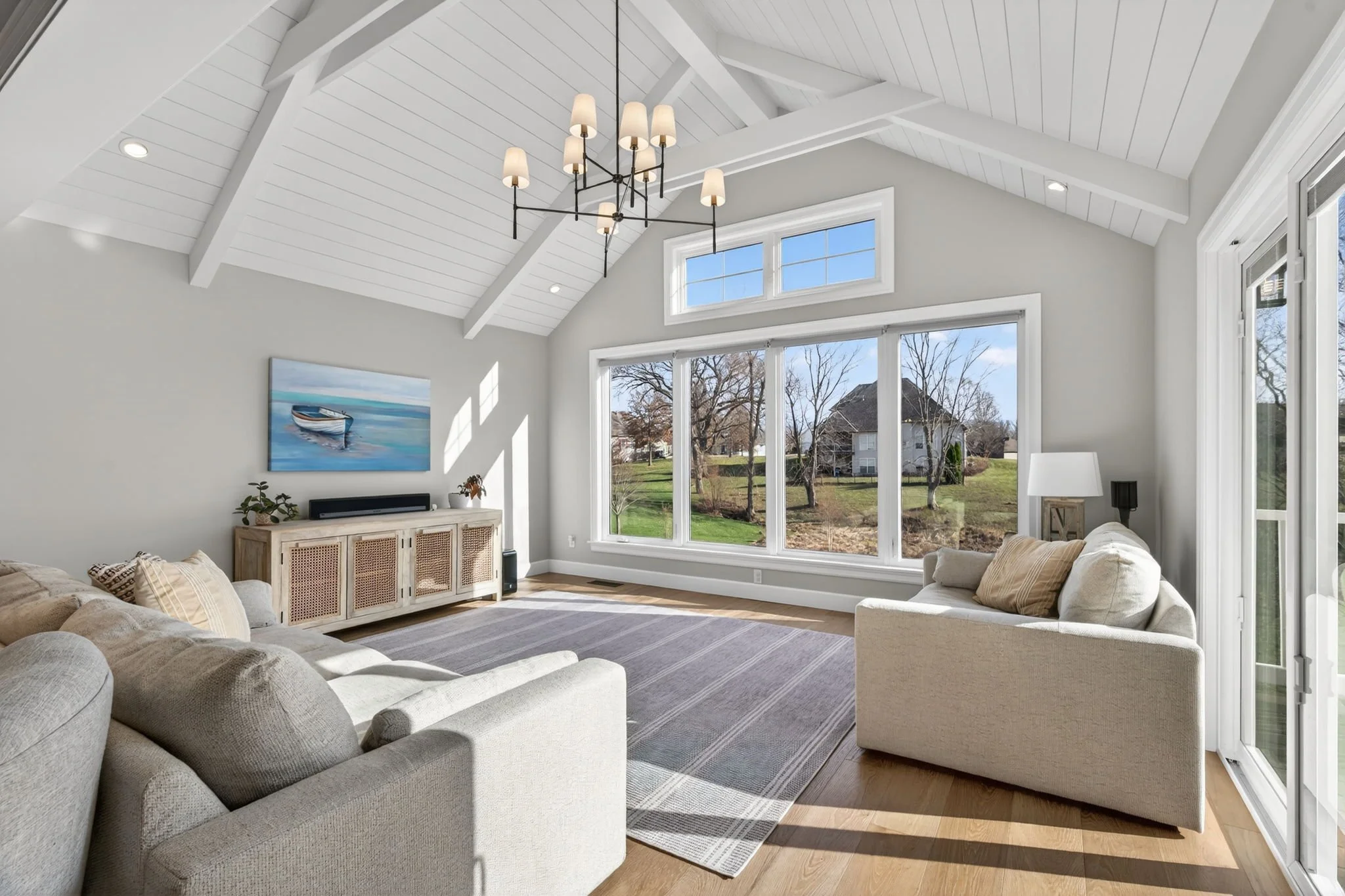 Vaulted great room with a black chandelier and sliding doors to the deck