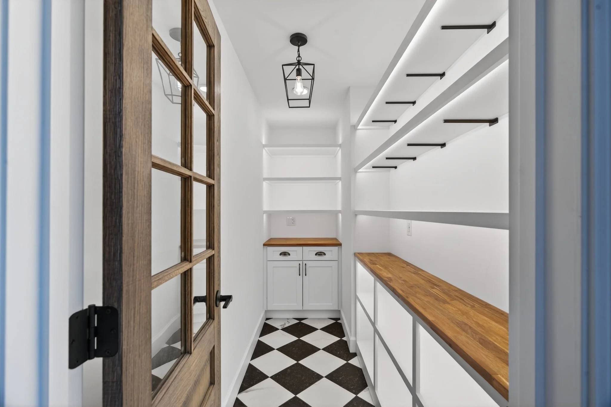 Walk-in pantry with a checkerboard floor and open shelving