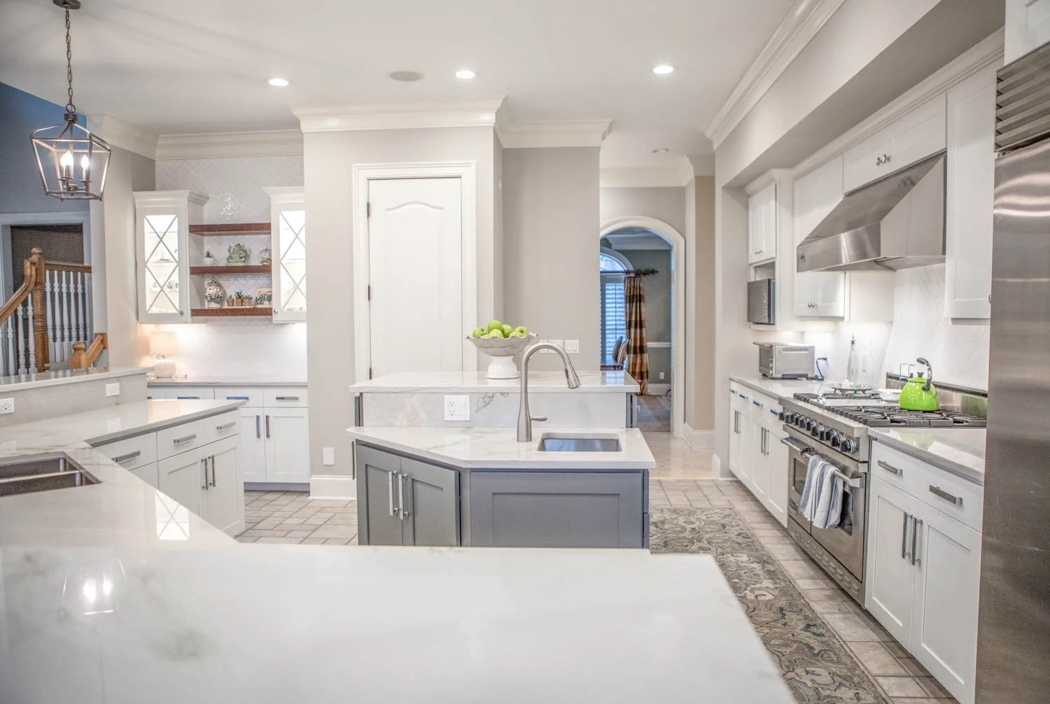 White kitchen remodel with a gray island and stainless appliances