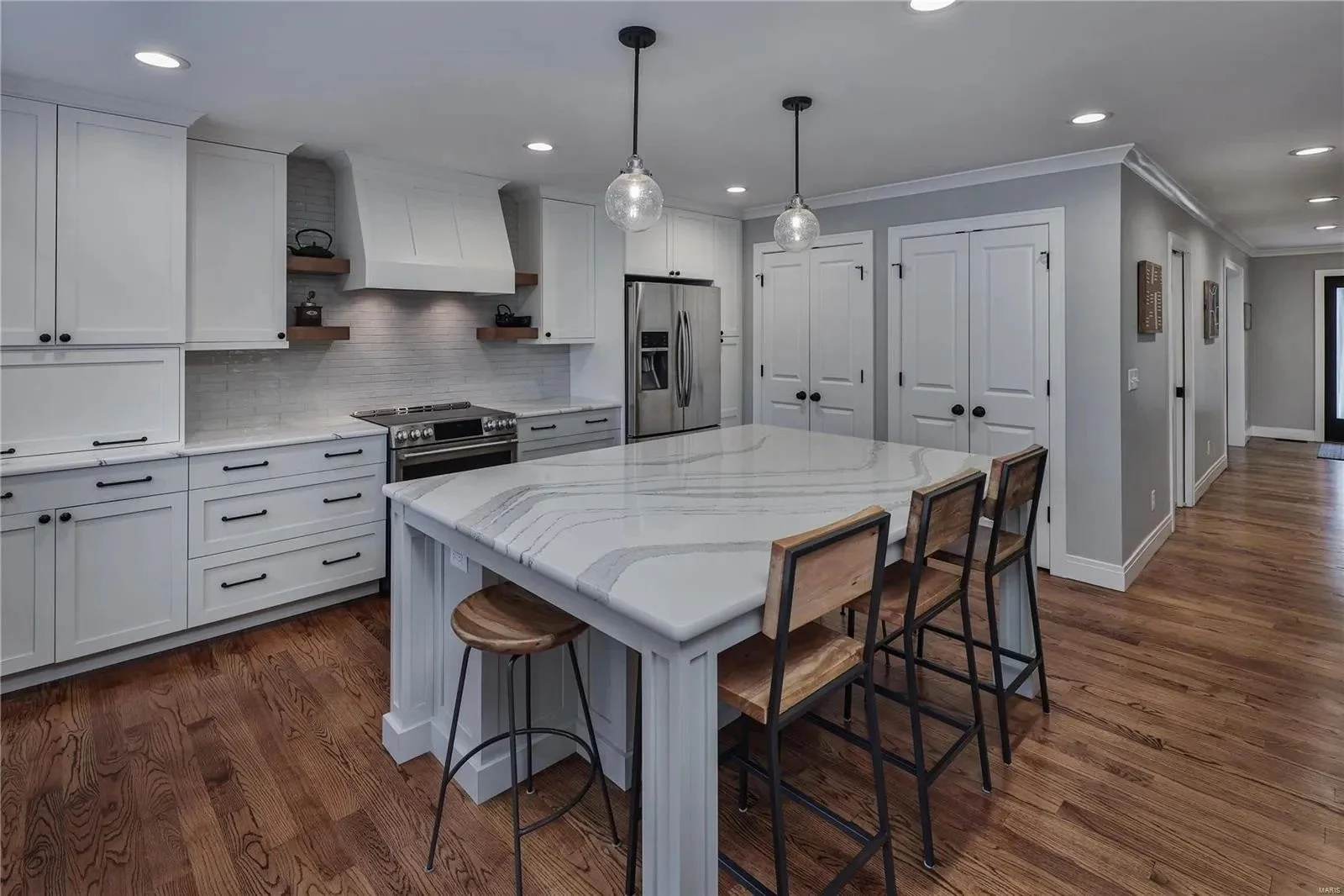 White kitchen cabinets with a range hood and large island