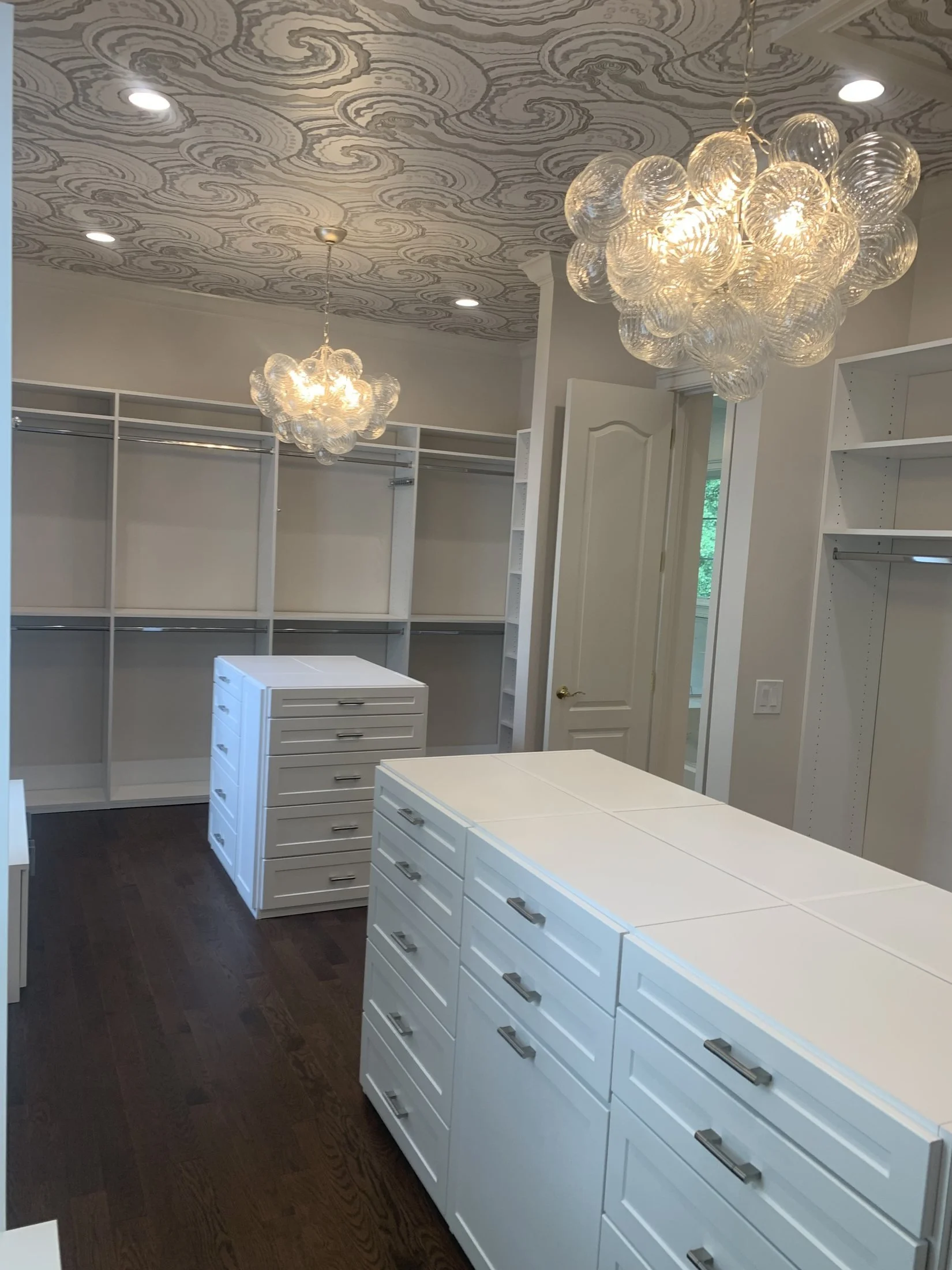 Custom walk-in closet with an island and chandelier