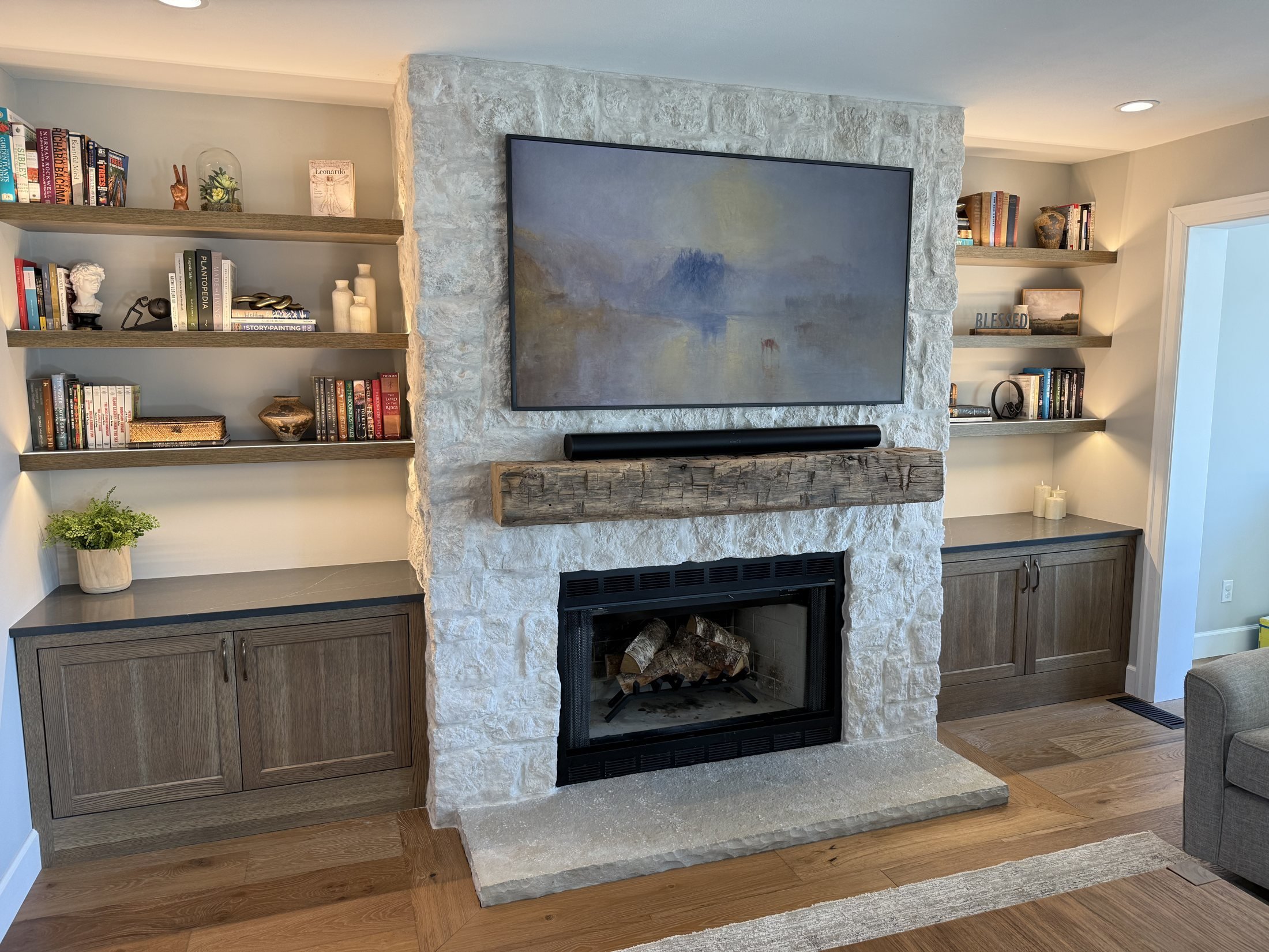 Built-in cabinets and floating shelves beside a stone fireplace