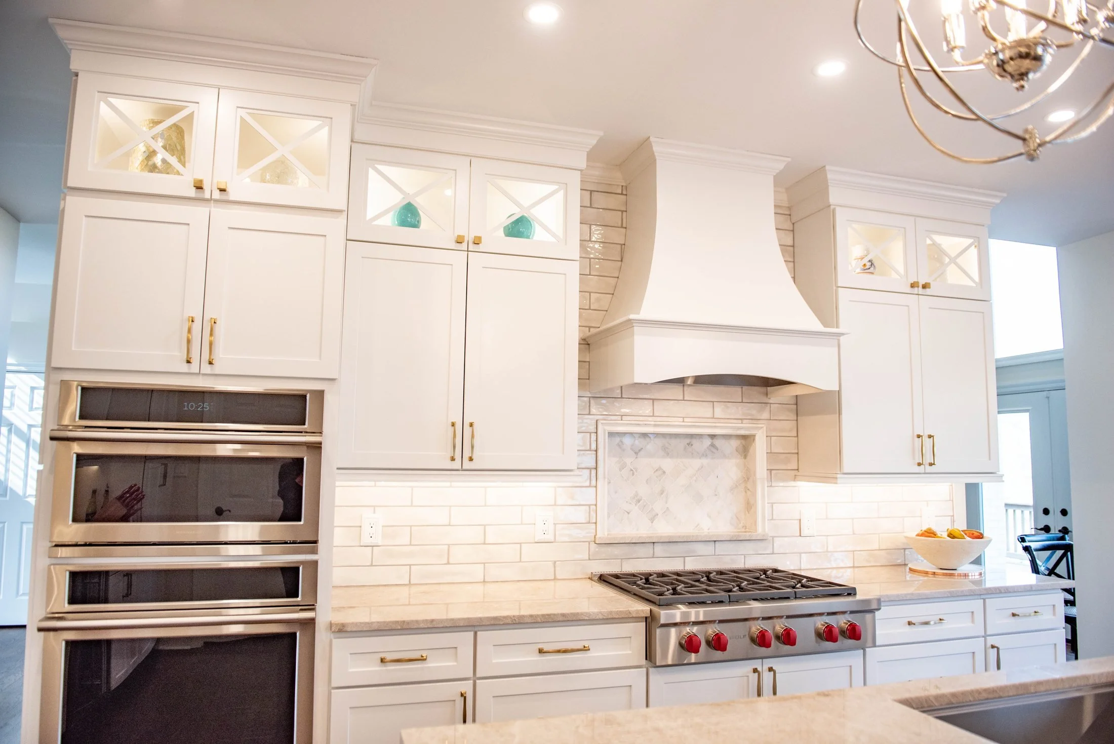 Double wall ovens beside a custom range hood