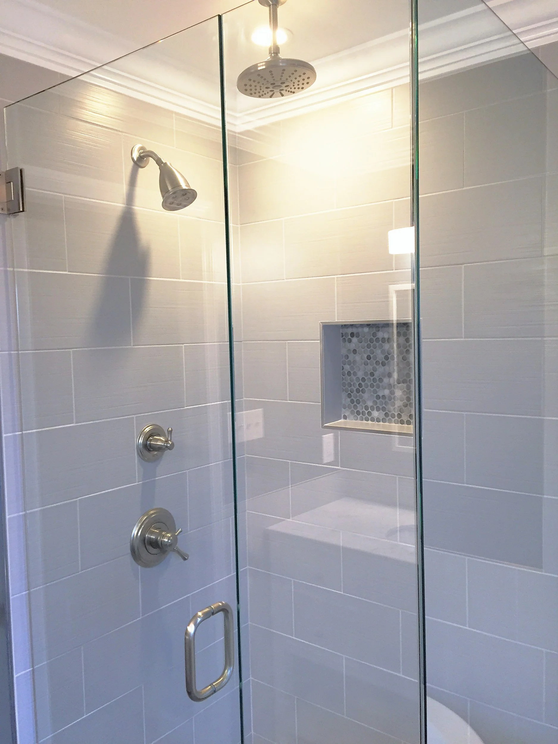 Gray tile shower with a frameless glass enclosure
