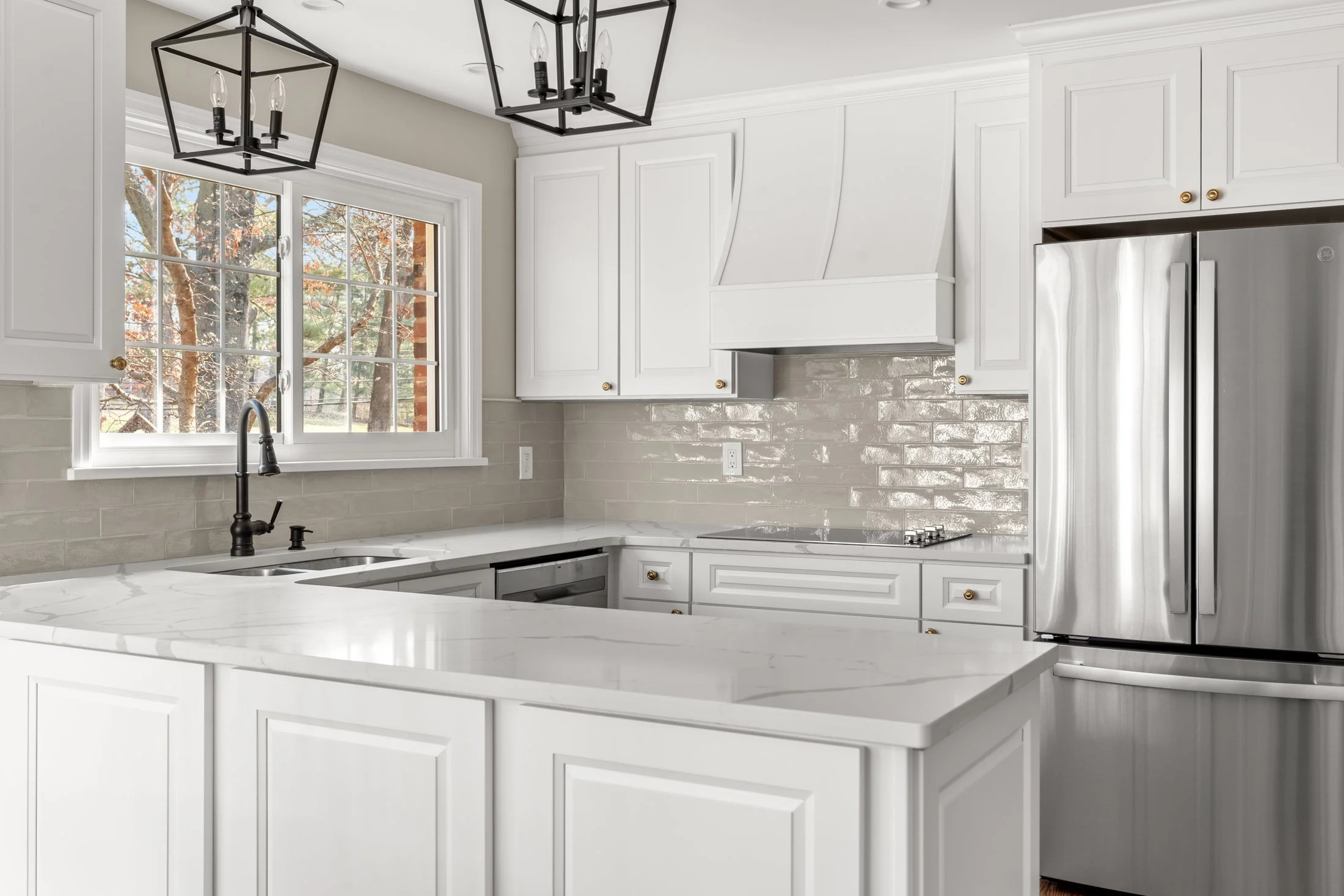 White cabinetry with a glossy tile backsplash and stainless refrigerator