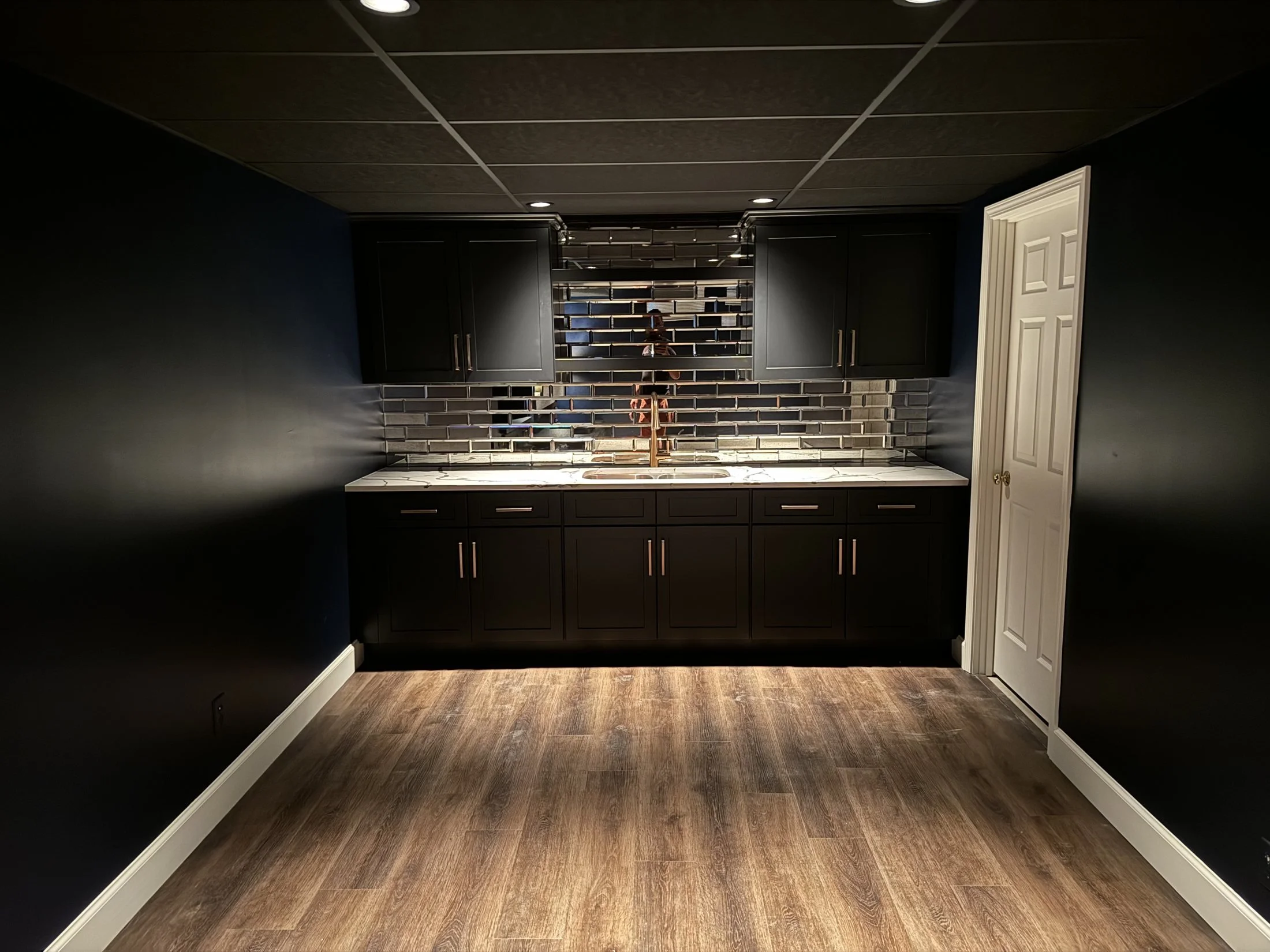 Black wet bar with a tile backsplash