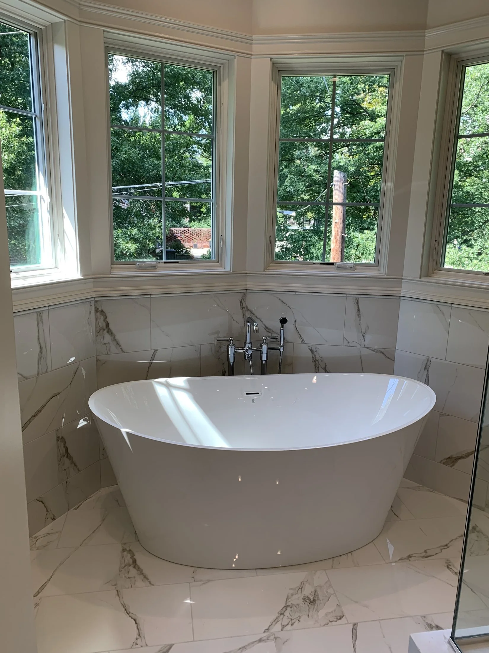 Freestanding soaking tub under a wall of windows