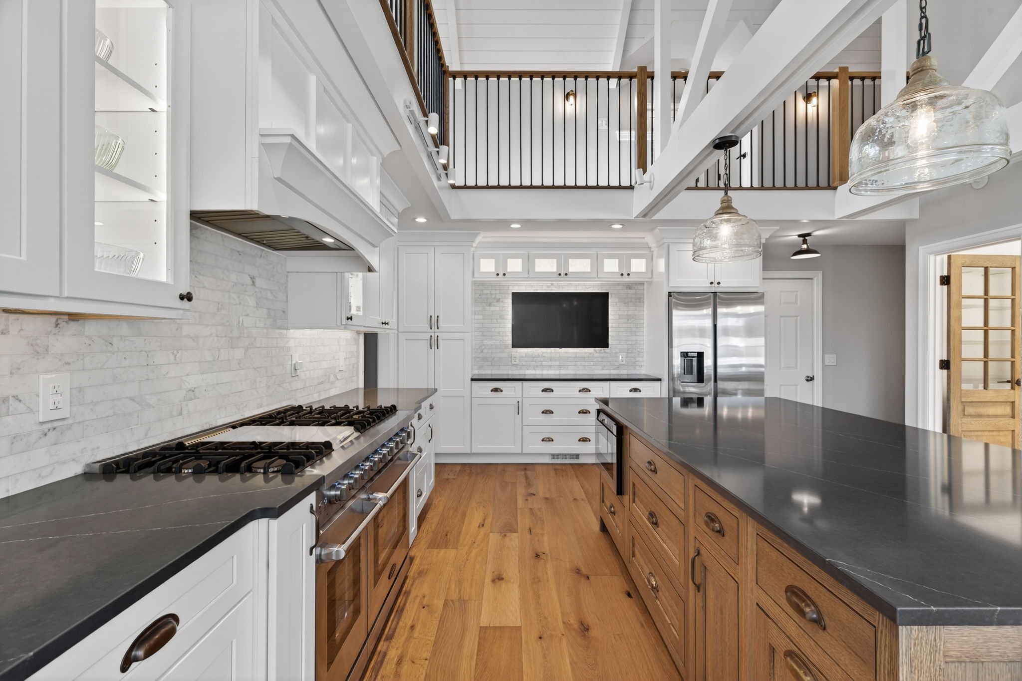 Professional gas range, wood island, and white cabinetry