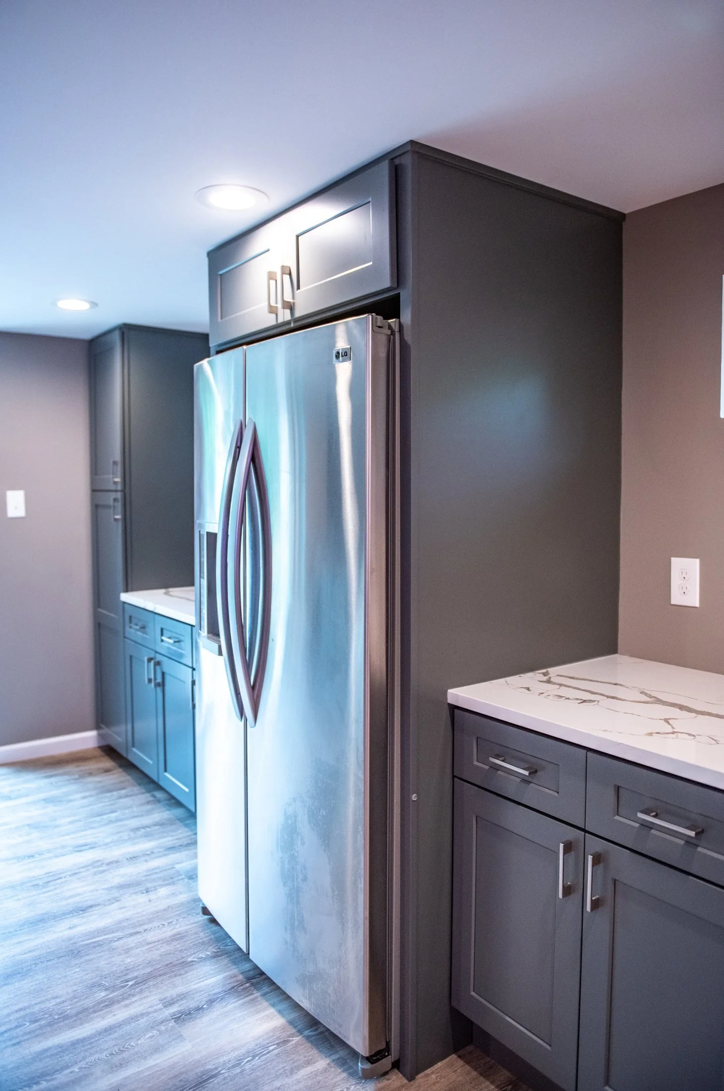 Built-in refrigerator beside gray cabinetry