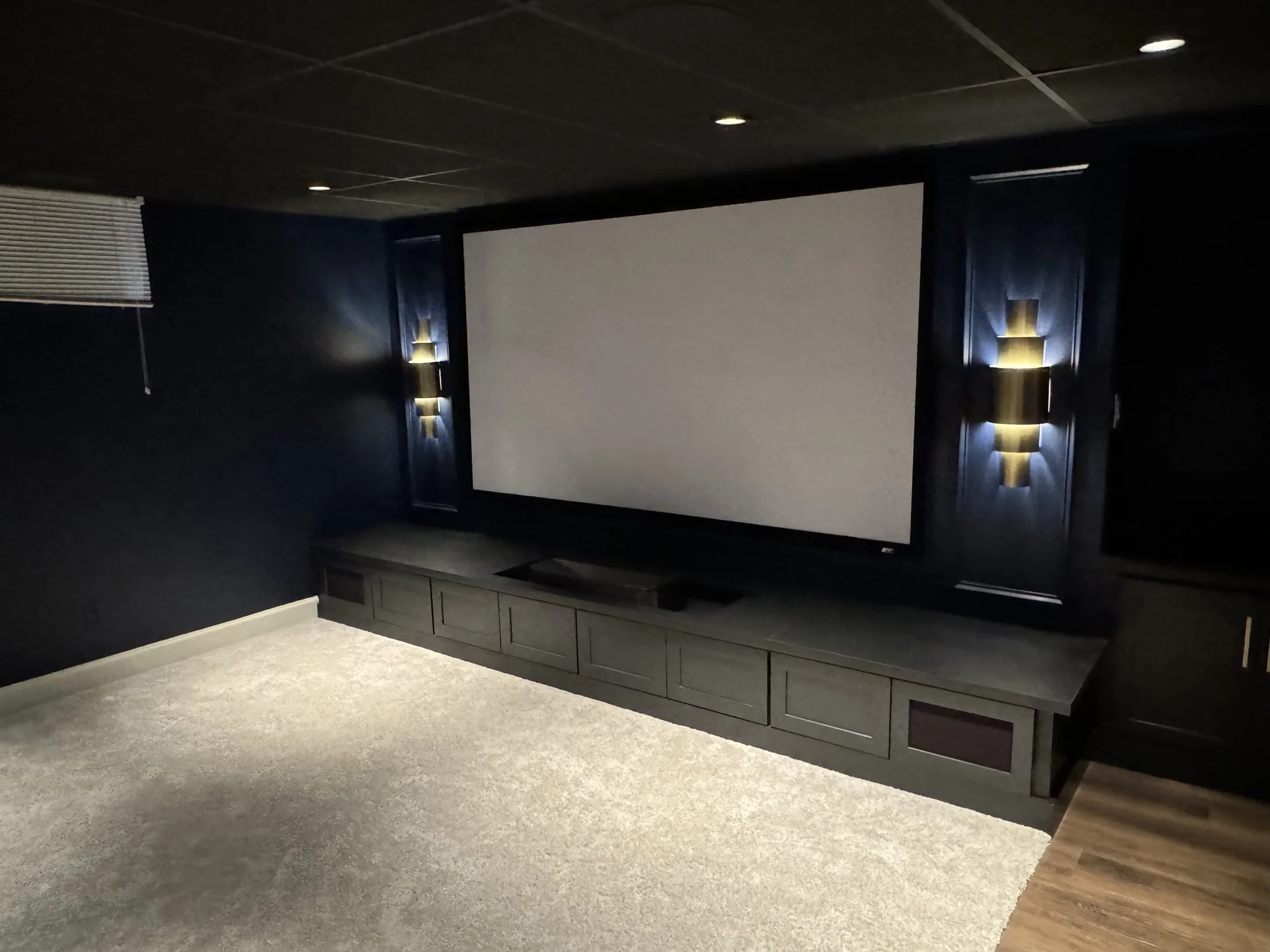 Basement home theater with a projection screen and sconces