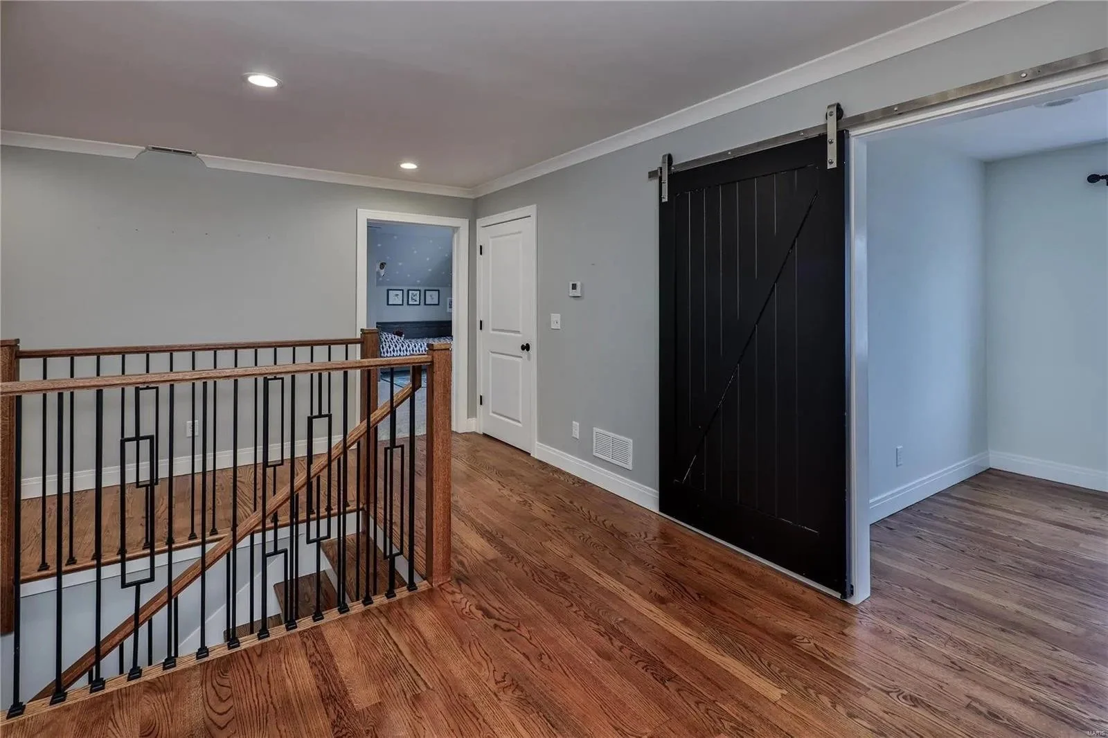 Upstairs landing with an iron railing and sliding barn door