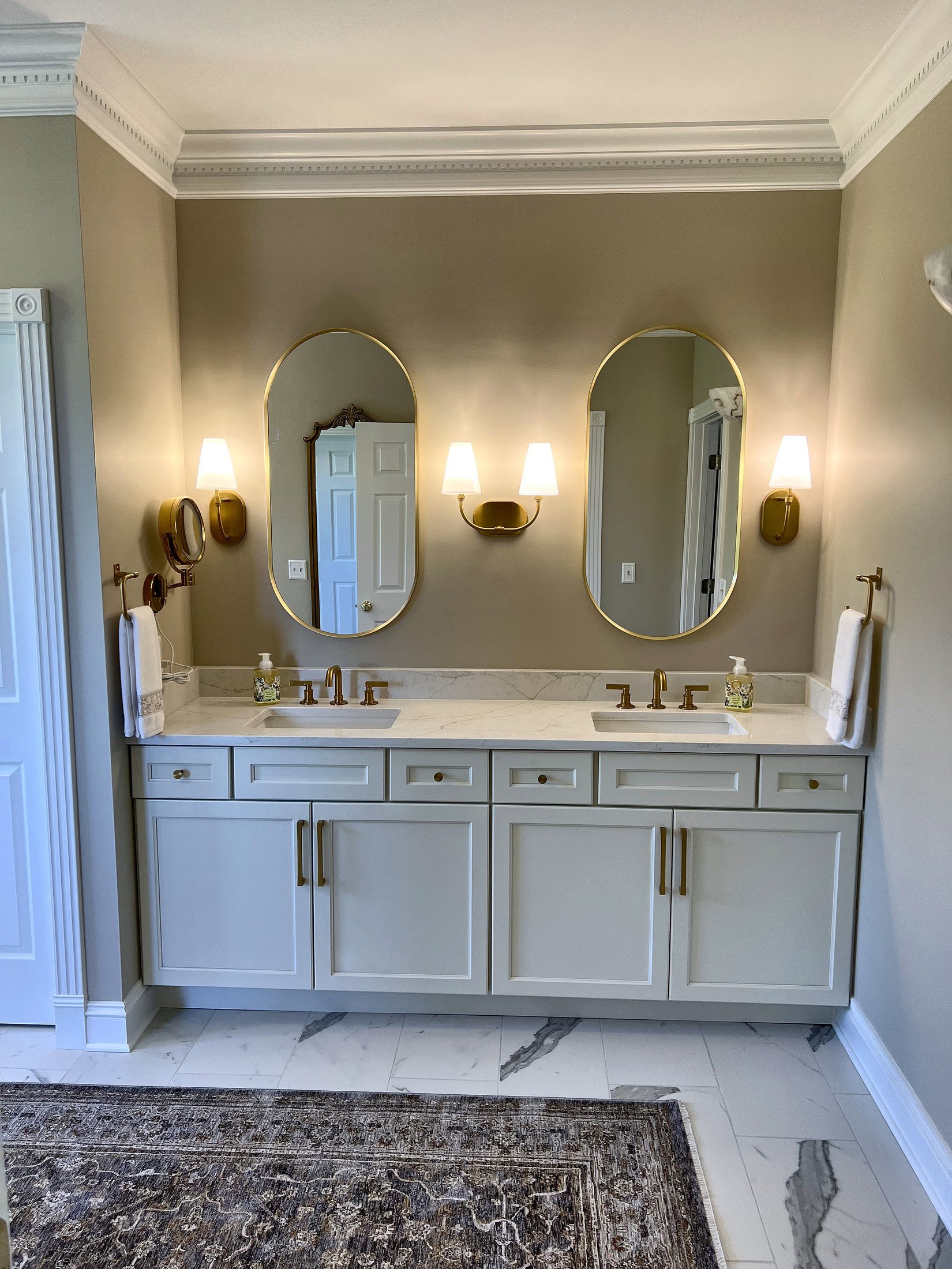Painted double vanity with oval mirrors and brass sconces