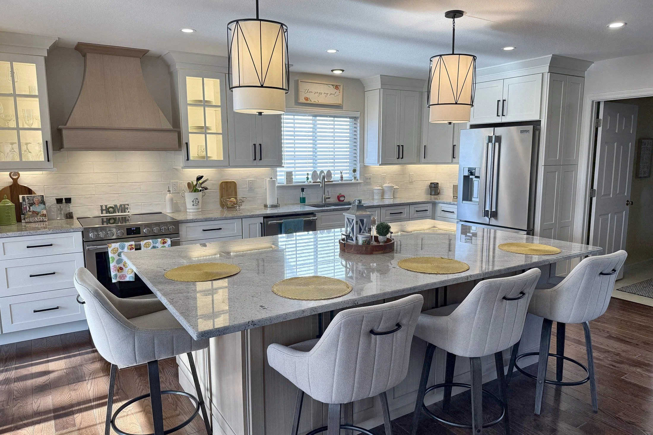 Open white kitchen with a large center island and a custom range hood