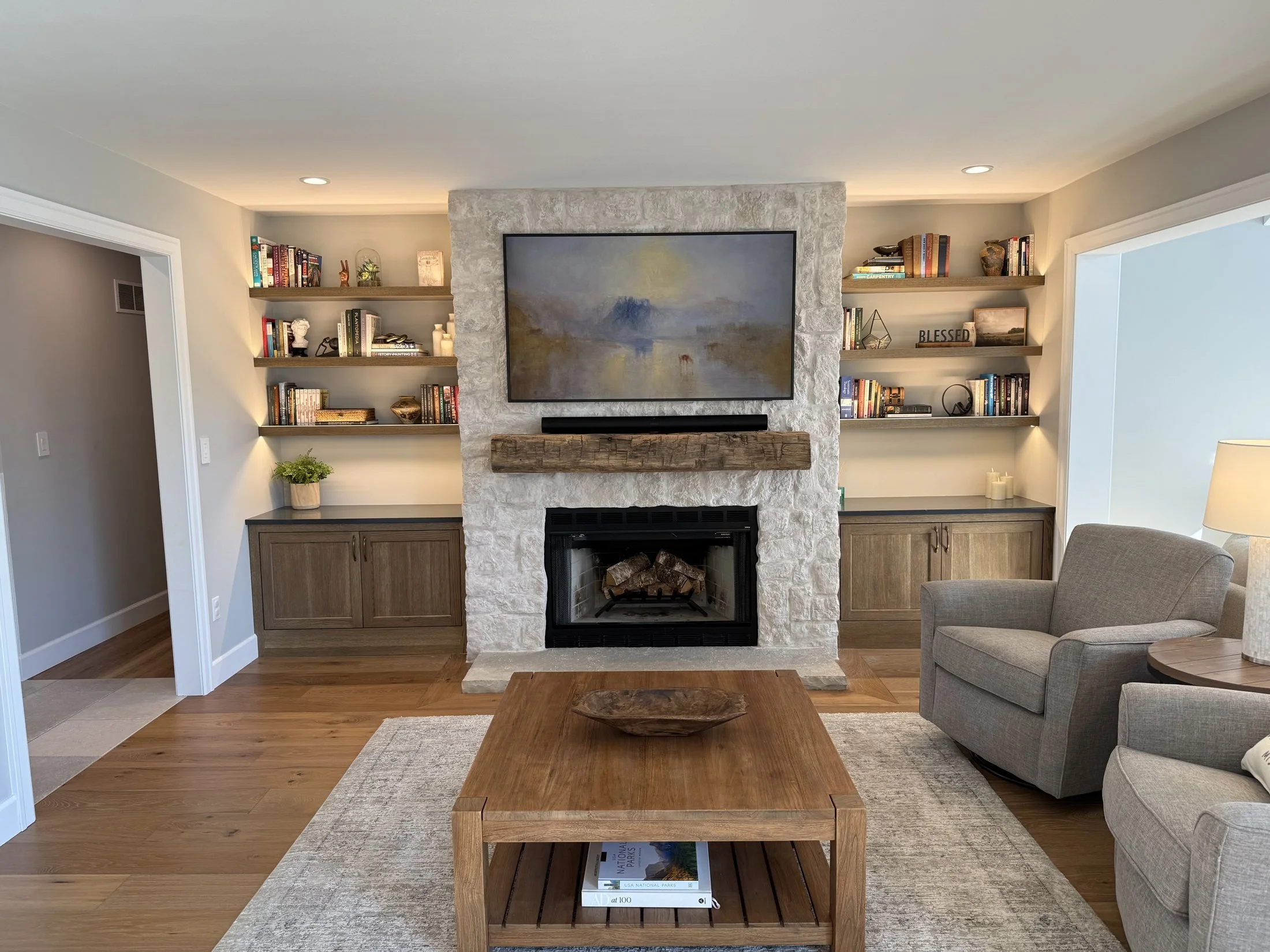 Family room with a stone fireplace and lit floating shelves