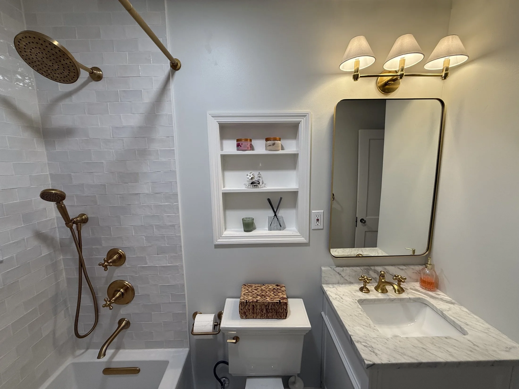 Guest bath with brushed brass fixtures and a recessed shelf