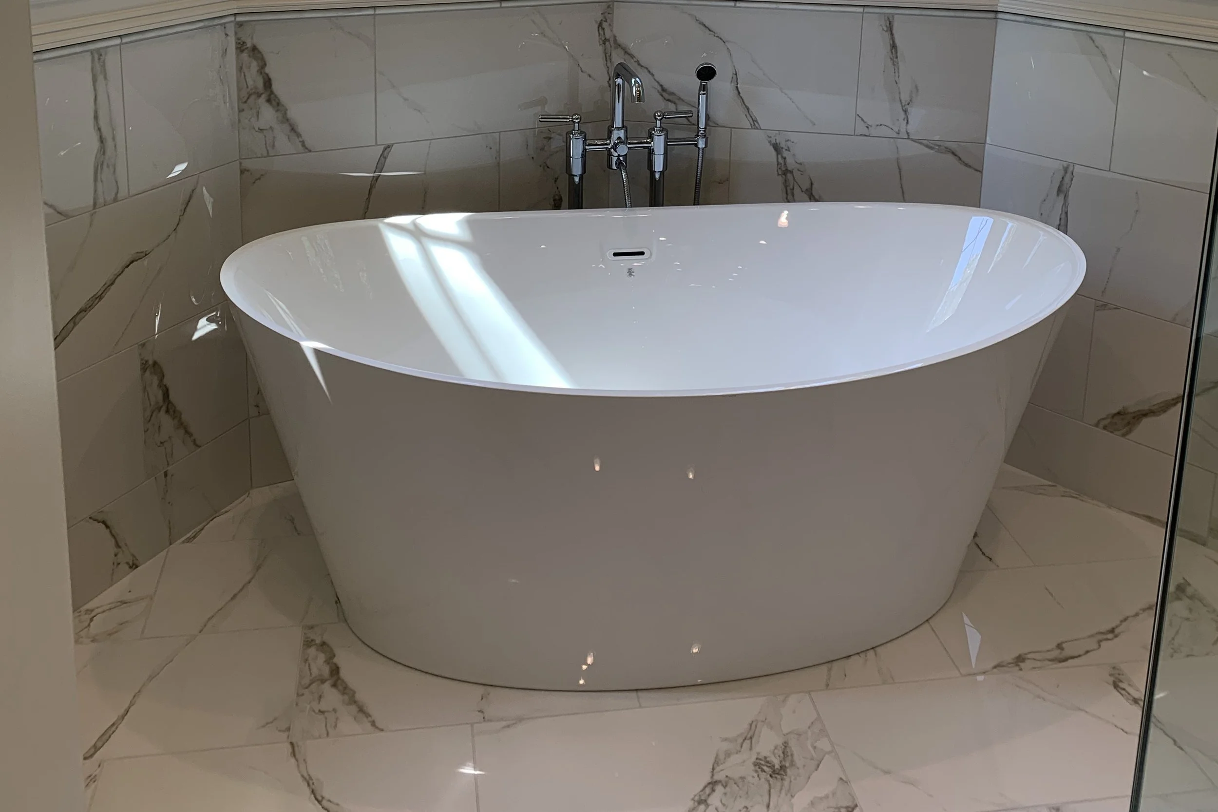 Primary bathroom with a freestanding tub and marble-look tile
