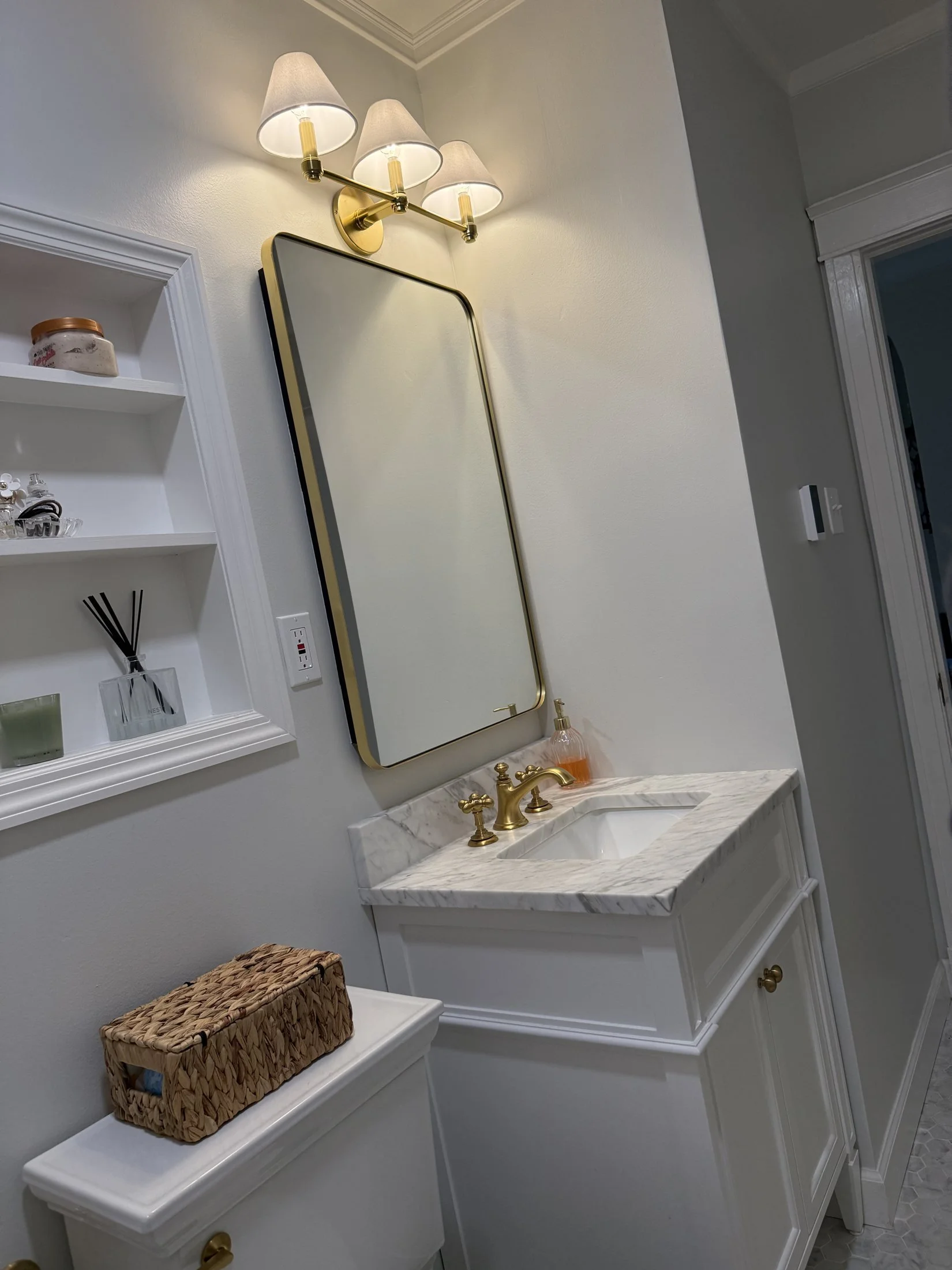 Brass vanity lights over an arched mirror