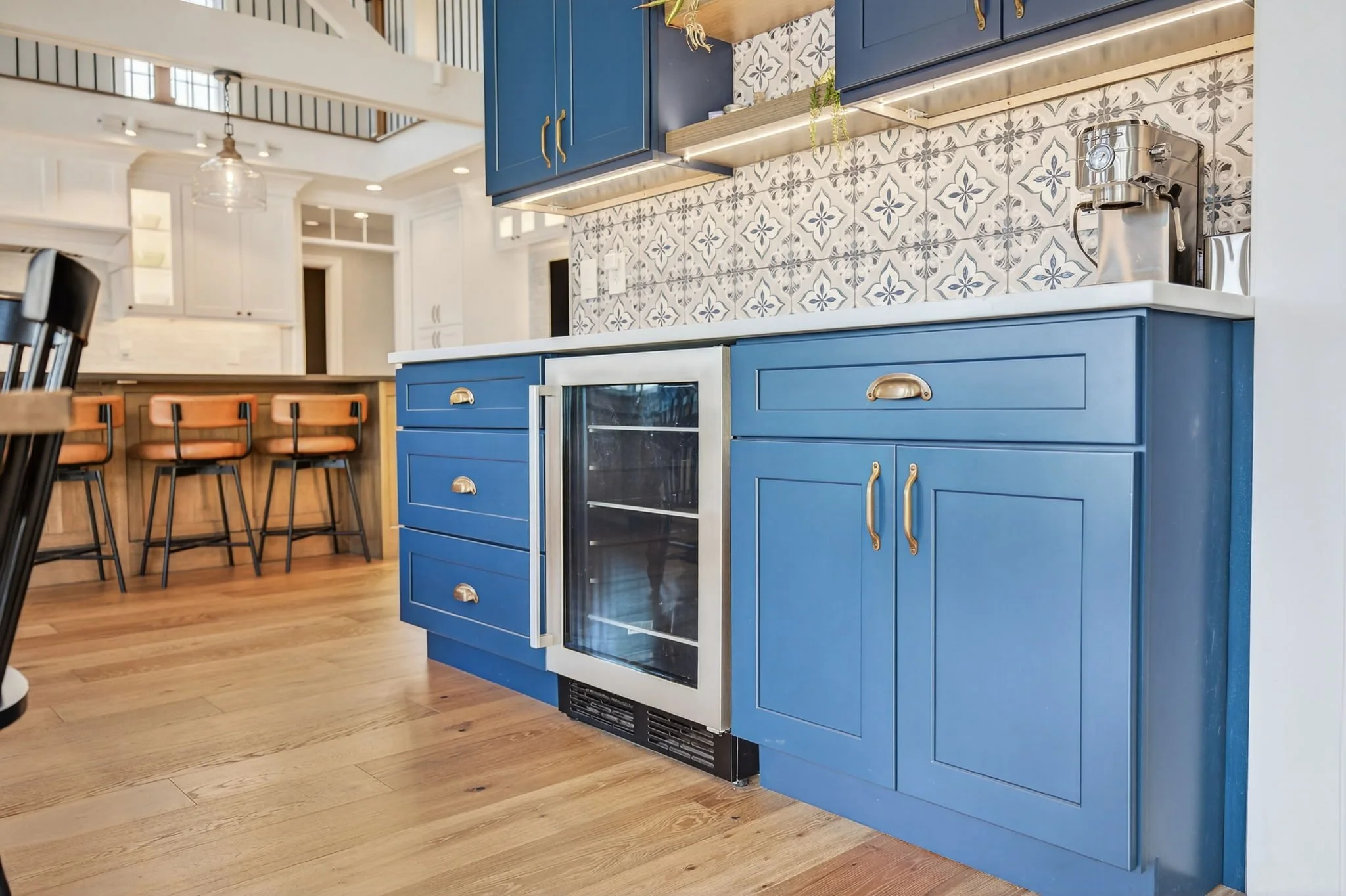 Navy island cabinetry with a wine fridge and patterned tile