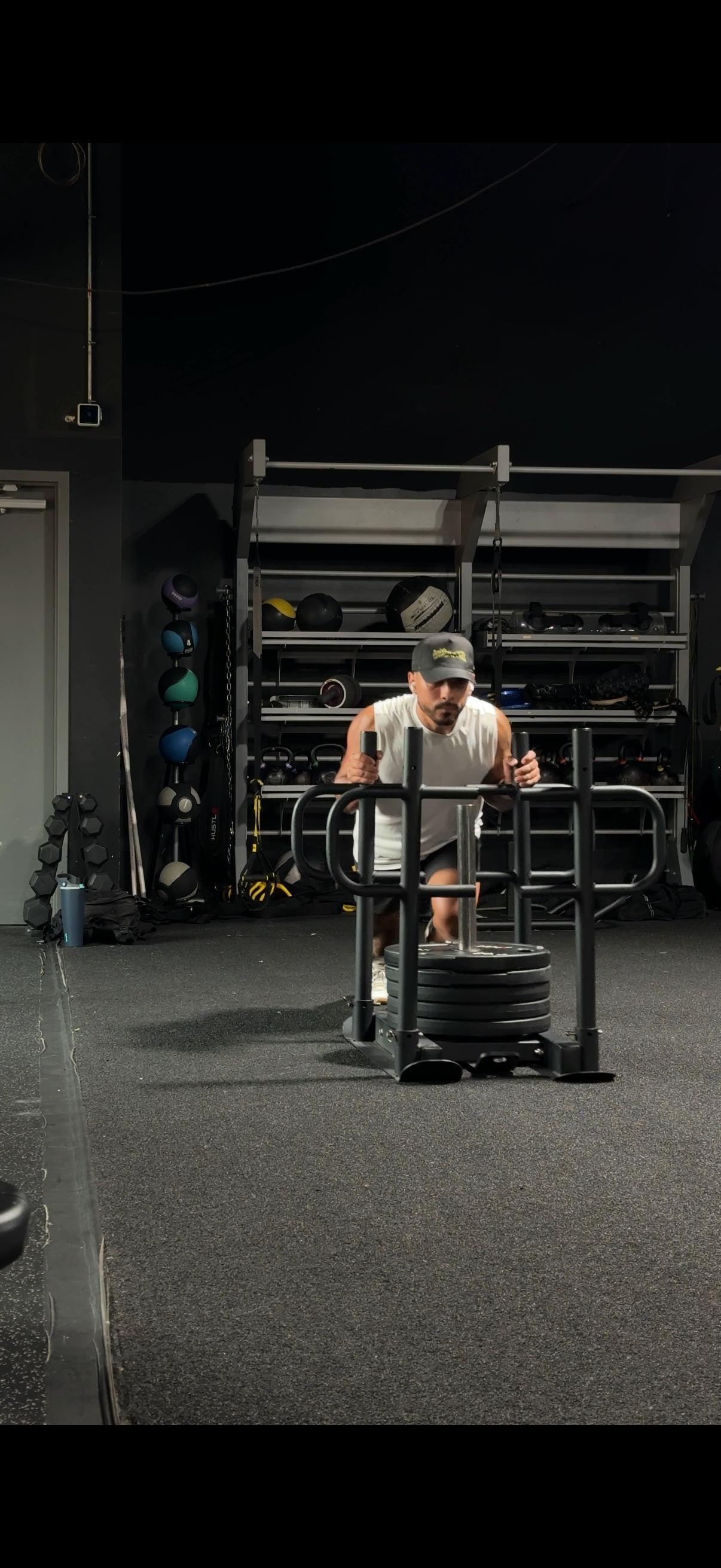 A person pushing a sled with weights in a gym.