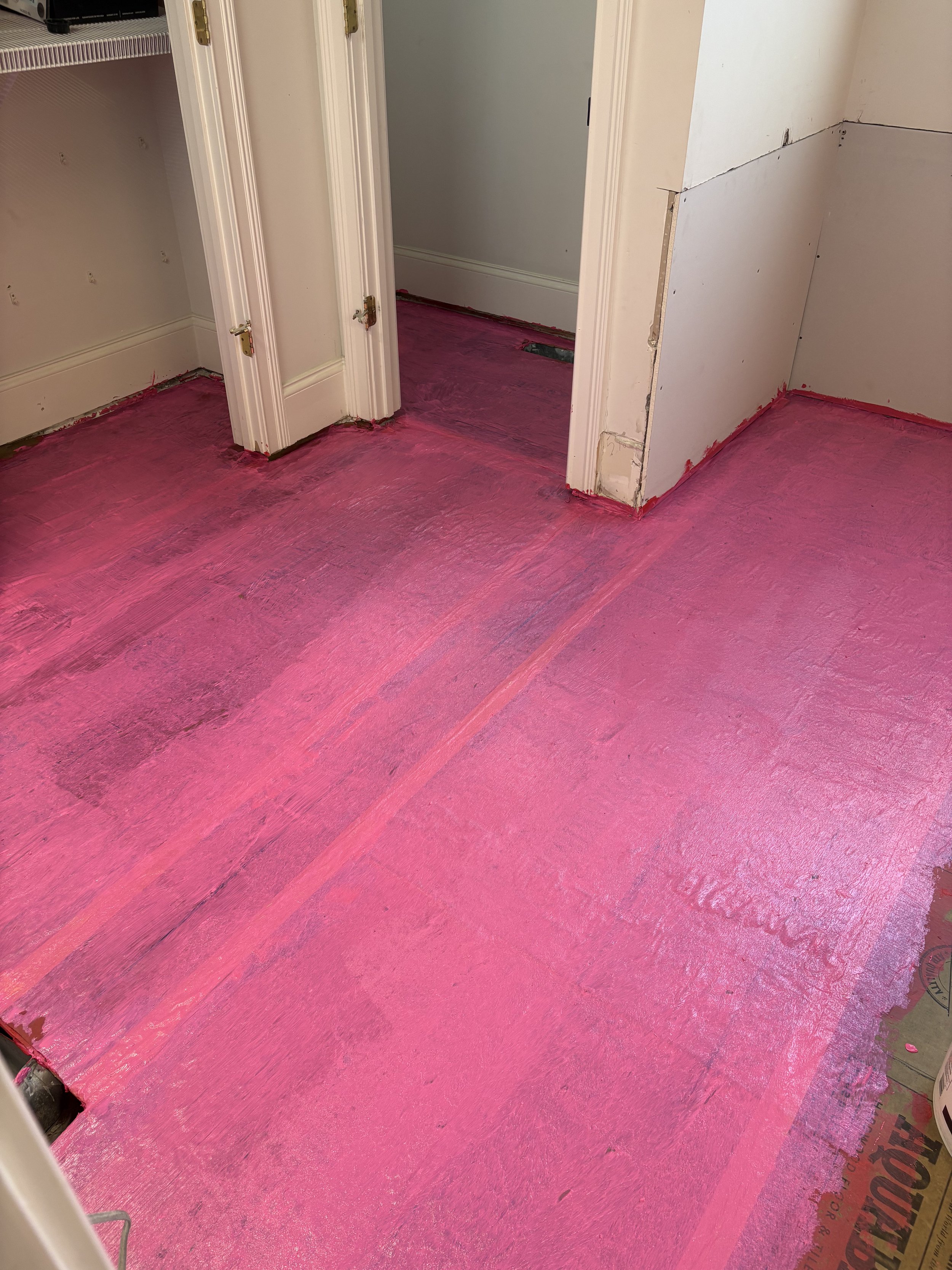 Room with pink protective floor covering in the process of renovation, with partially finished walls and doorway.