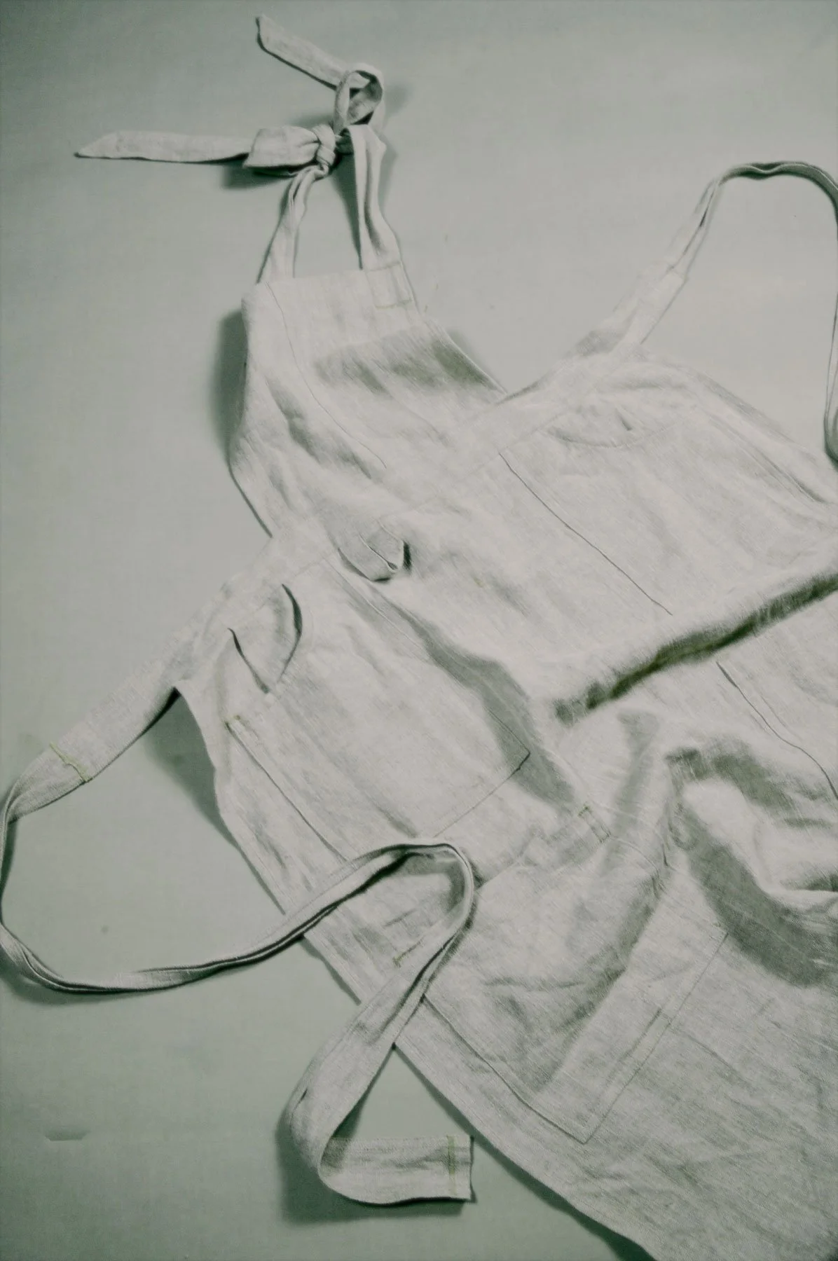 A drawing of a white apron, with a pocket on the front, lying on a flat surface.