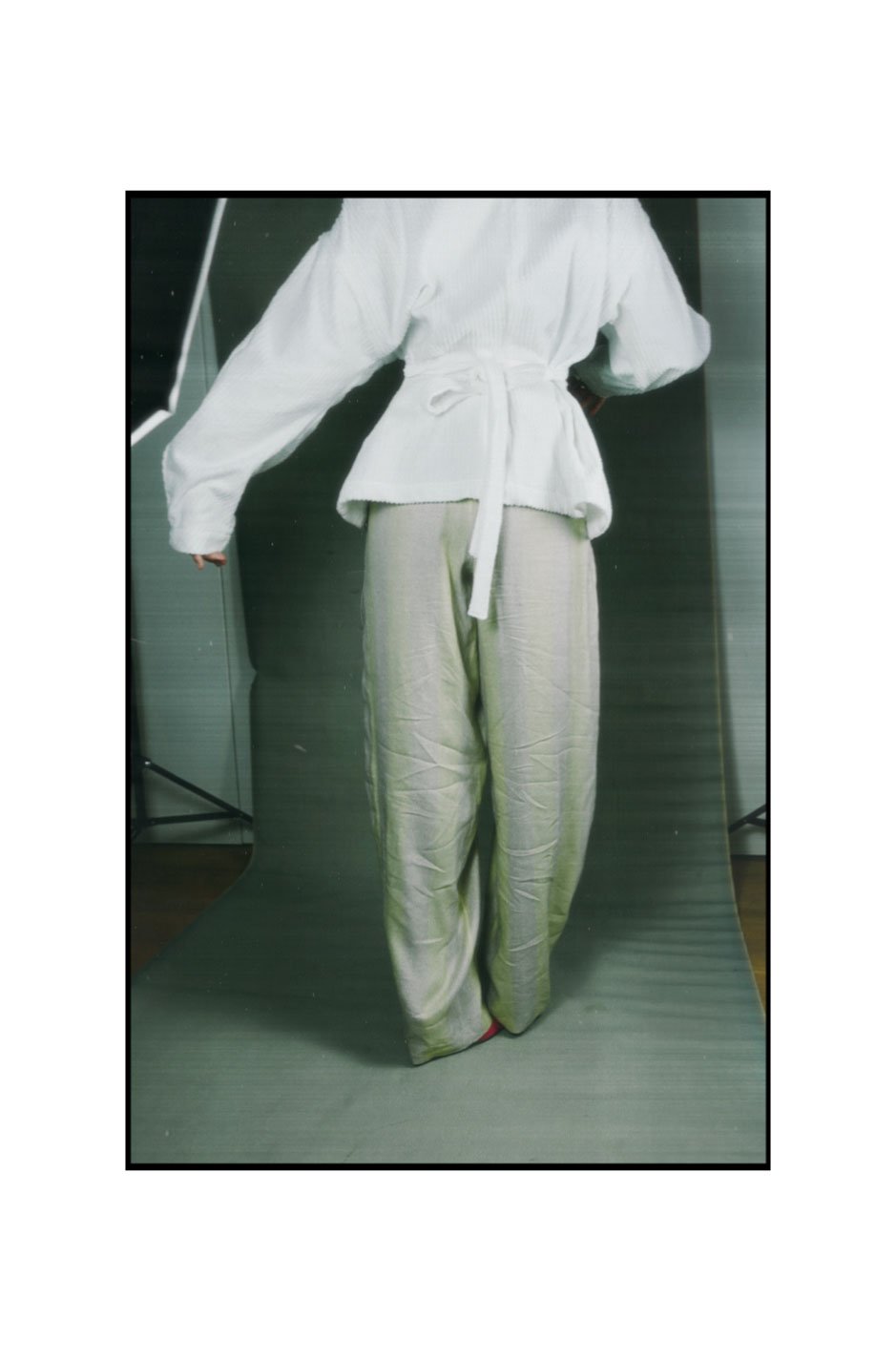 A person wearing a white martial arts gi with a belt, standing in front of a dark backdrop.