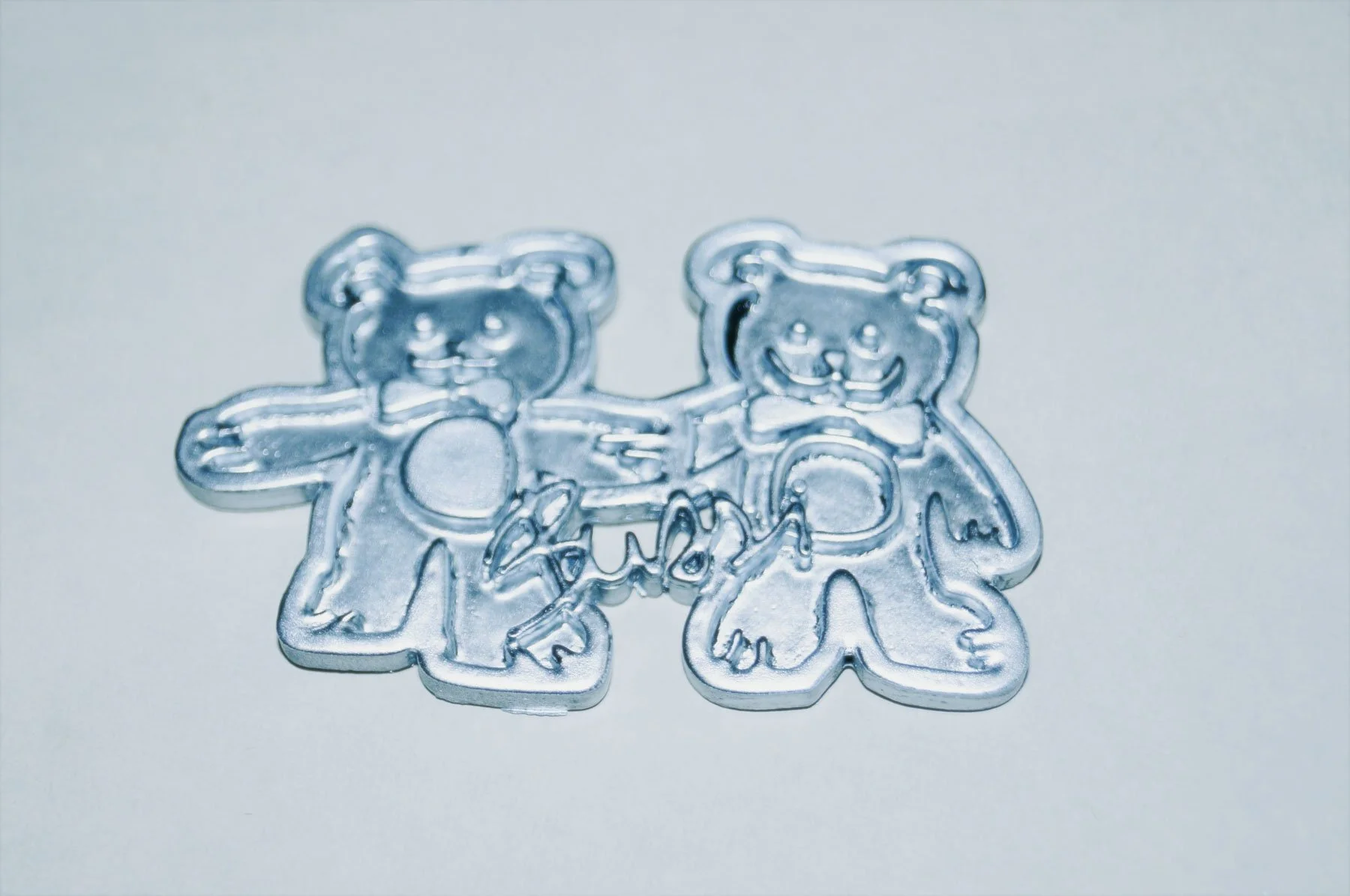 Clear plastic cookie cutters shaped like teddy bears with bows.