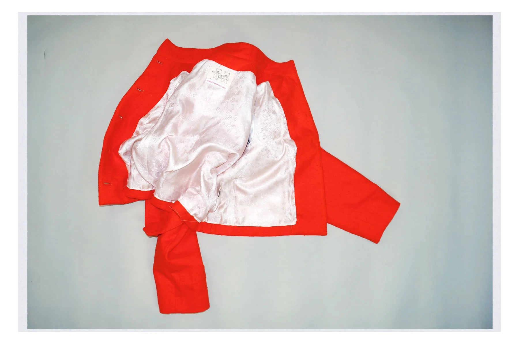 A red jacket with a satin lining draped over a white surface.