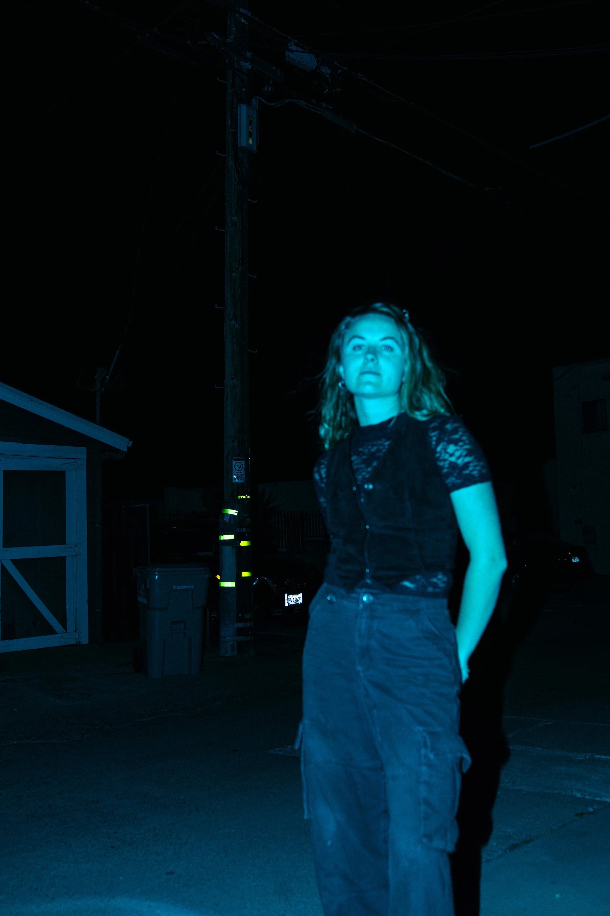 blue toned nighttime portrait with direct flash in an alley, cinematic nightlife photography