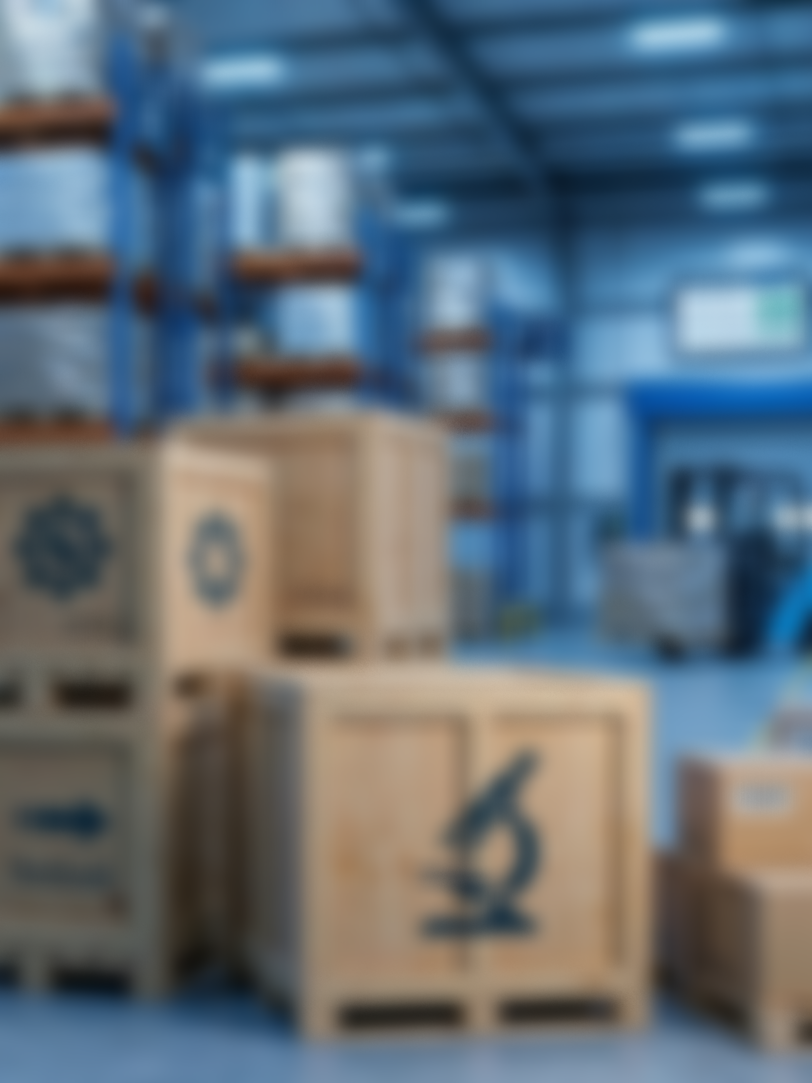 Stacks of wooden crates and boxes in a warehouse with blue metal shelving.