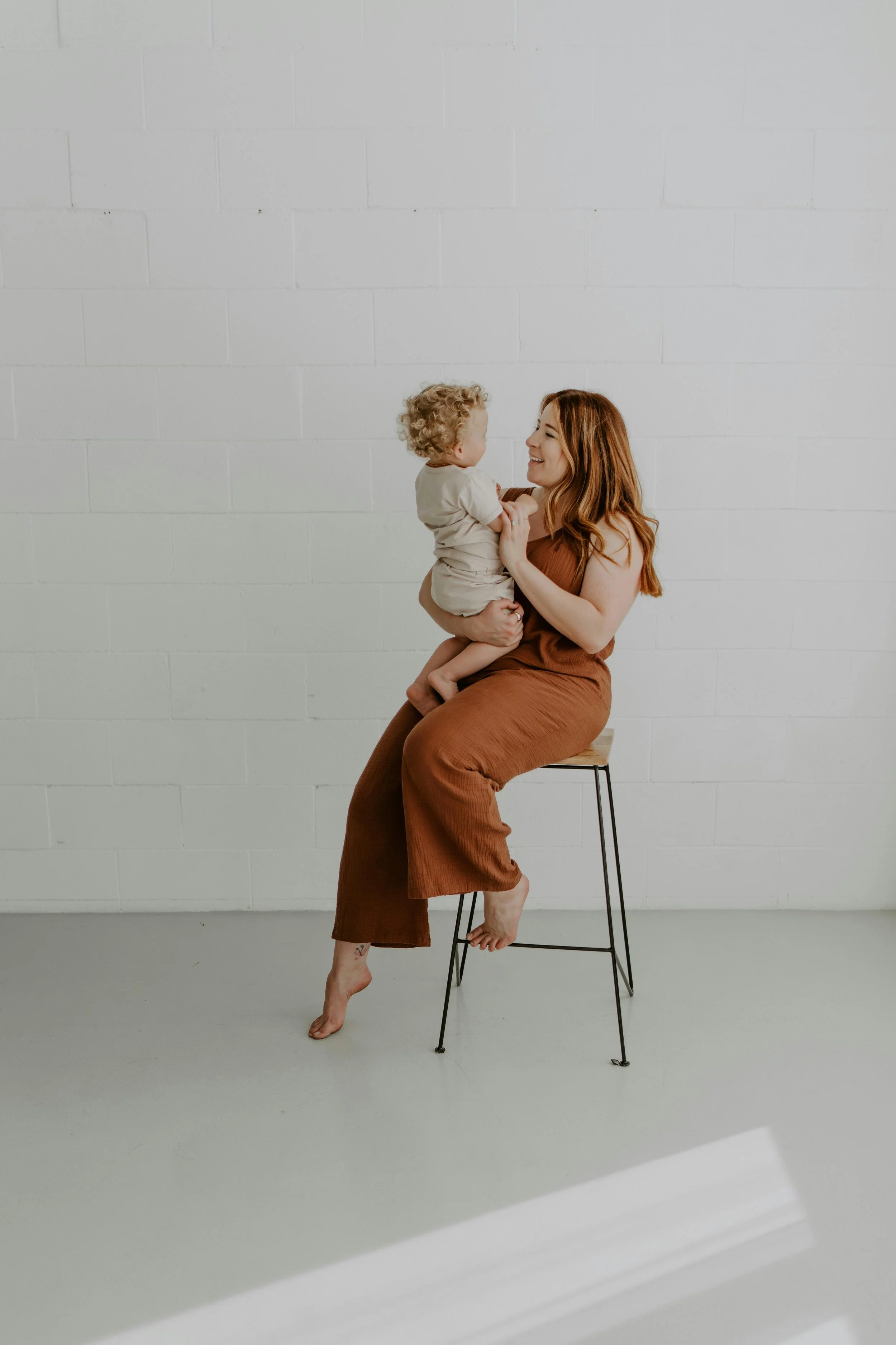 Mom holding baby son inside smiling