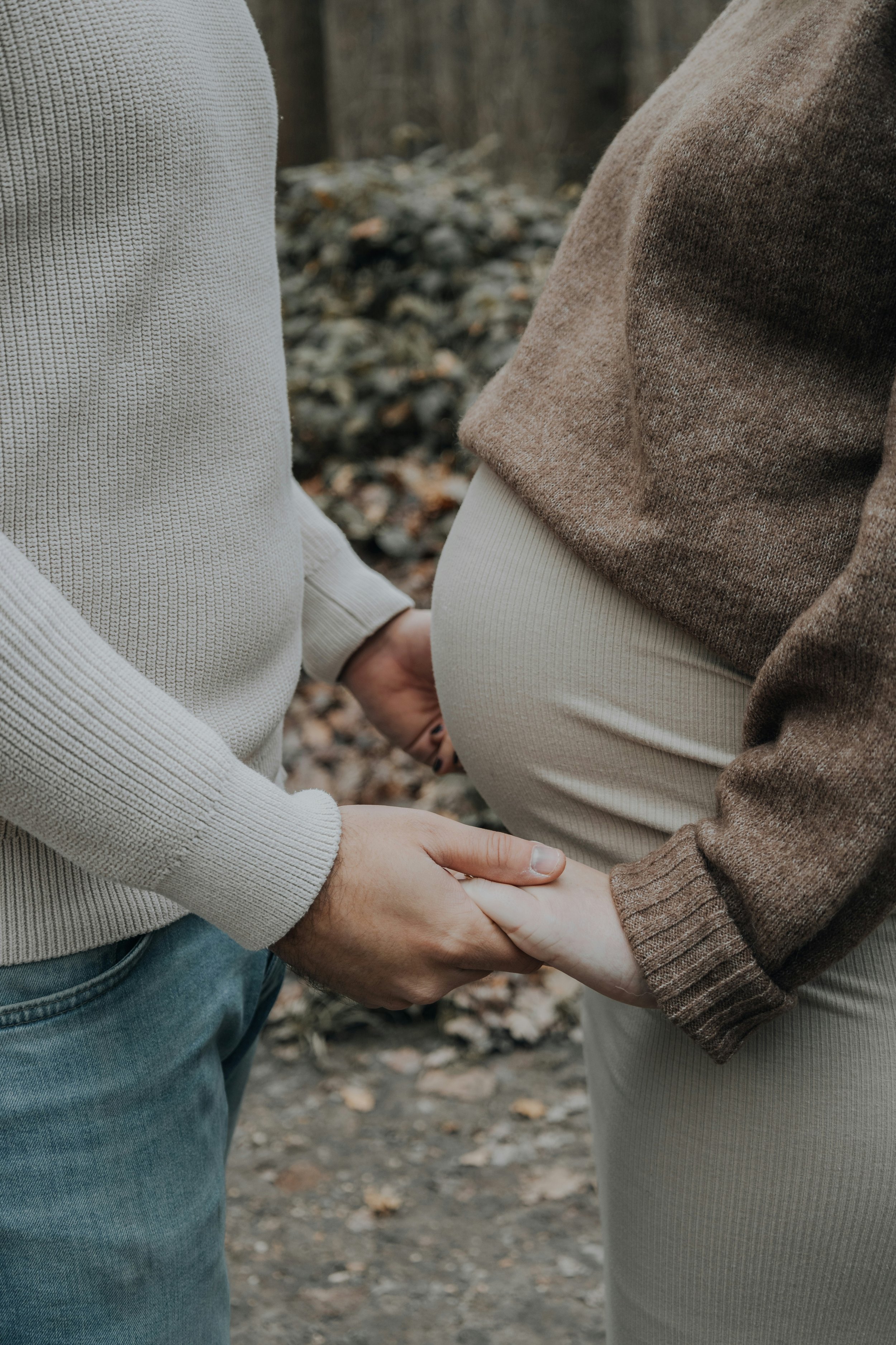 young couple close up holding hands with woman pregnant belly