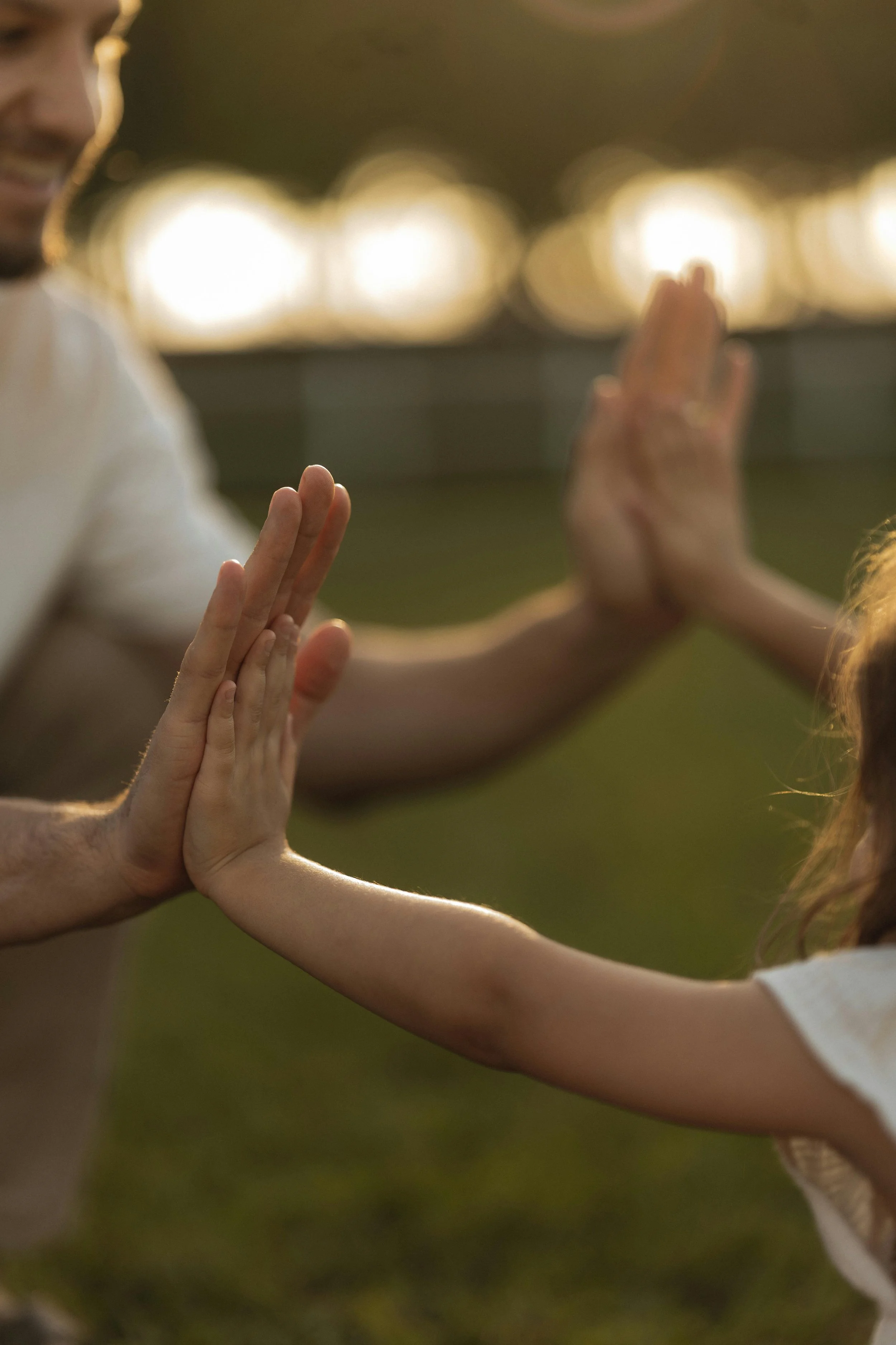 Father and child touching hands in sunlight